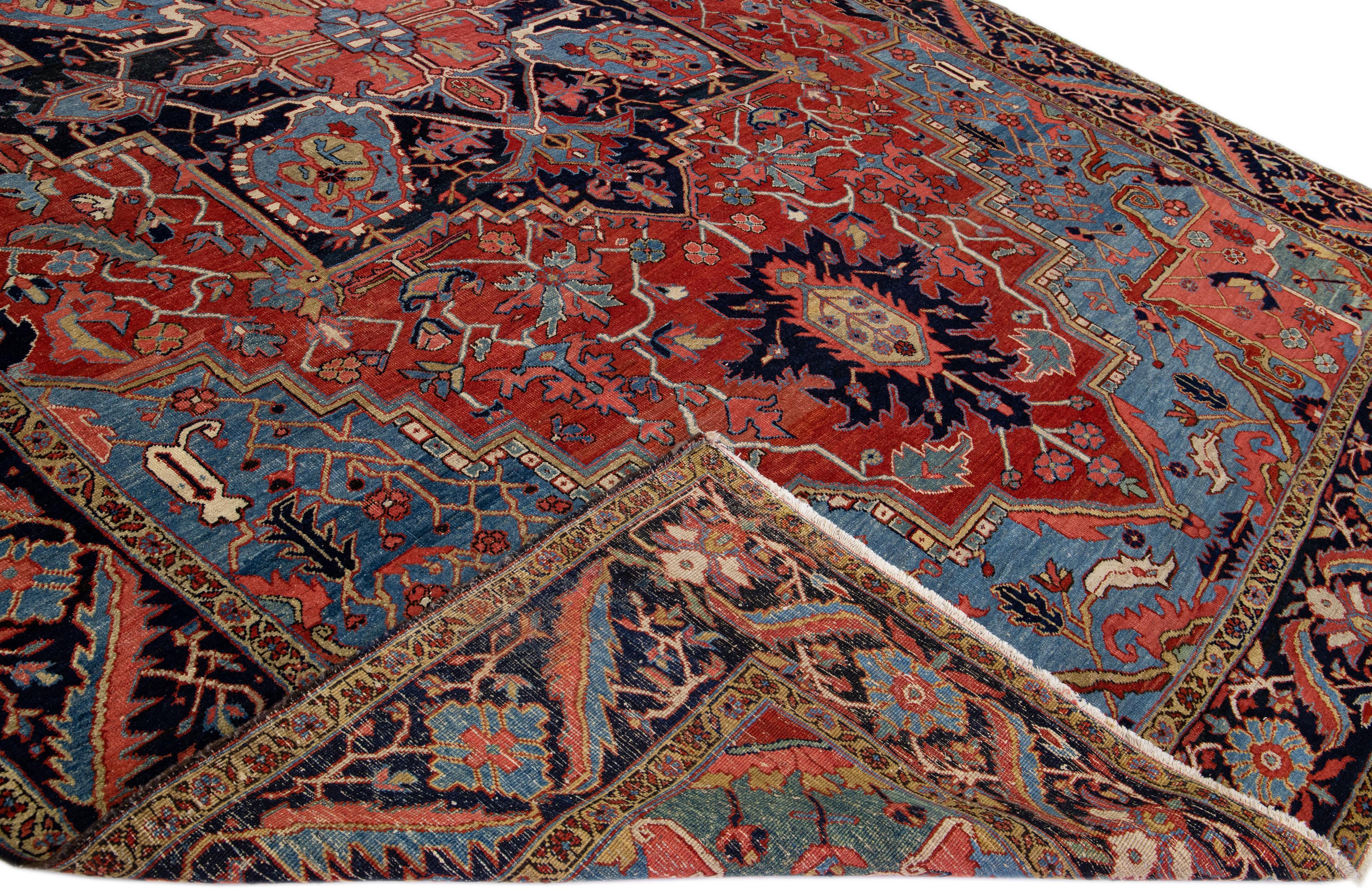 Beautiful antique Heriz hand-knotted oversized wool rug with a red and blue field. This Heriz rug has multi-color accents in a gorgeous all-over medallion floral design.

This rug measures: 11'9