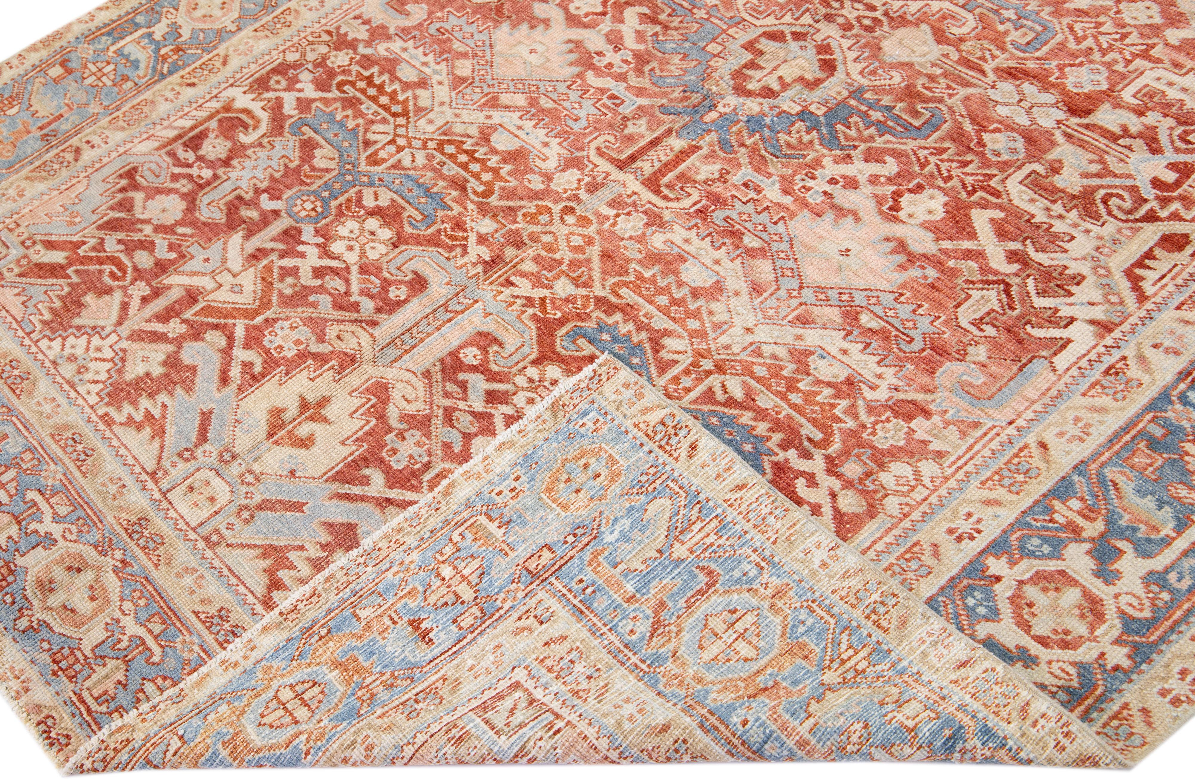 Beautiful antique Heriz hand-knotted wool rug with a rust red color field. This Persian rug has a blue frame with peach accents in a gorgeous all-over floral design.

This rug measures: 6'9