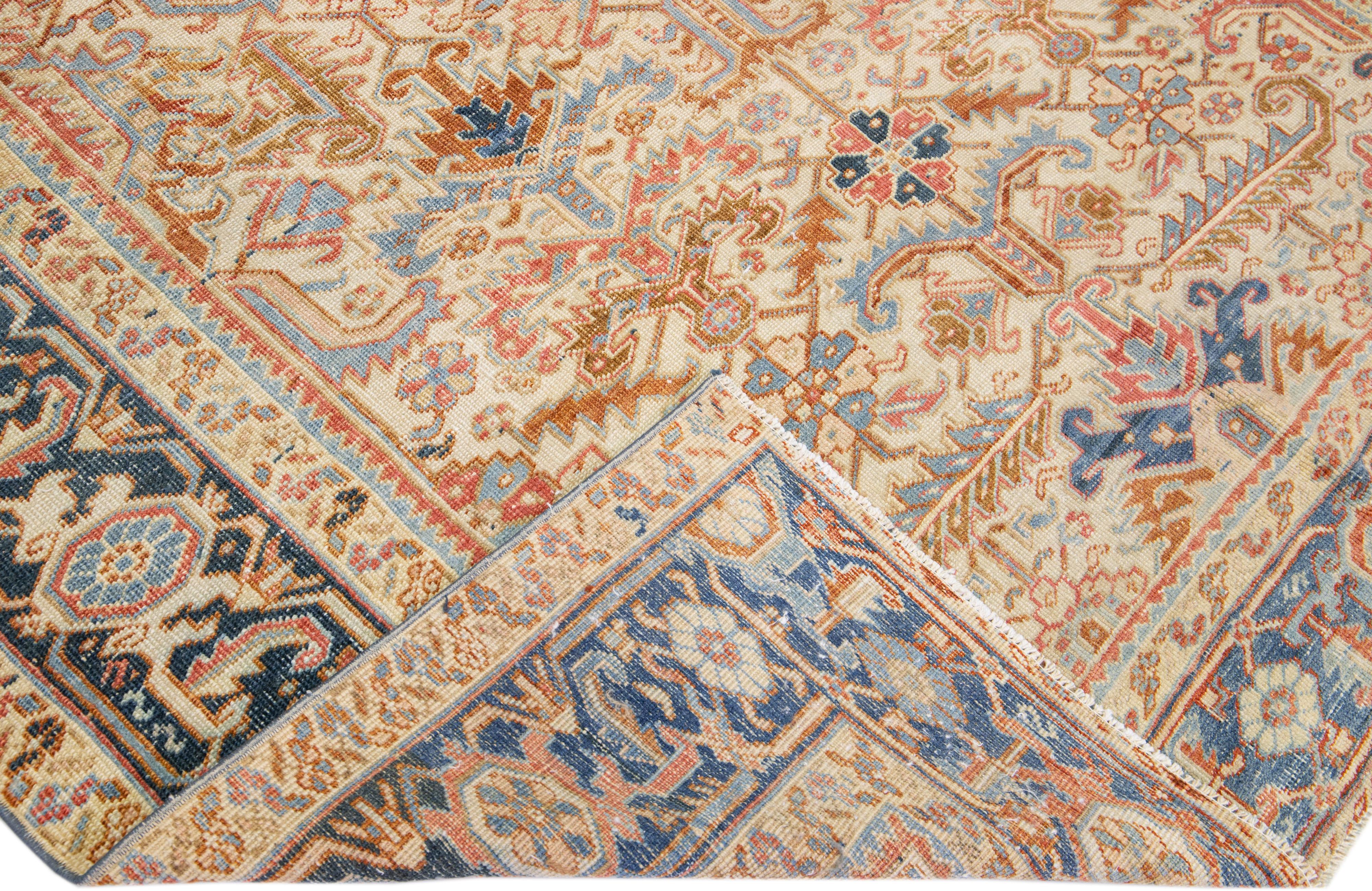 Beautiful antique Heriz hand-knotted wool rug with a rust color field. This Persian rug has a blue frame with tan and beige accents in a gorgeous all-over geometric floral medallion design.

This rug measures: 7'5