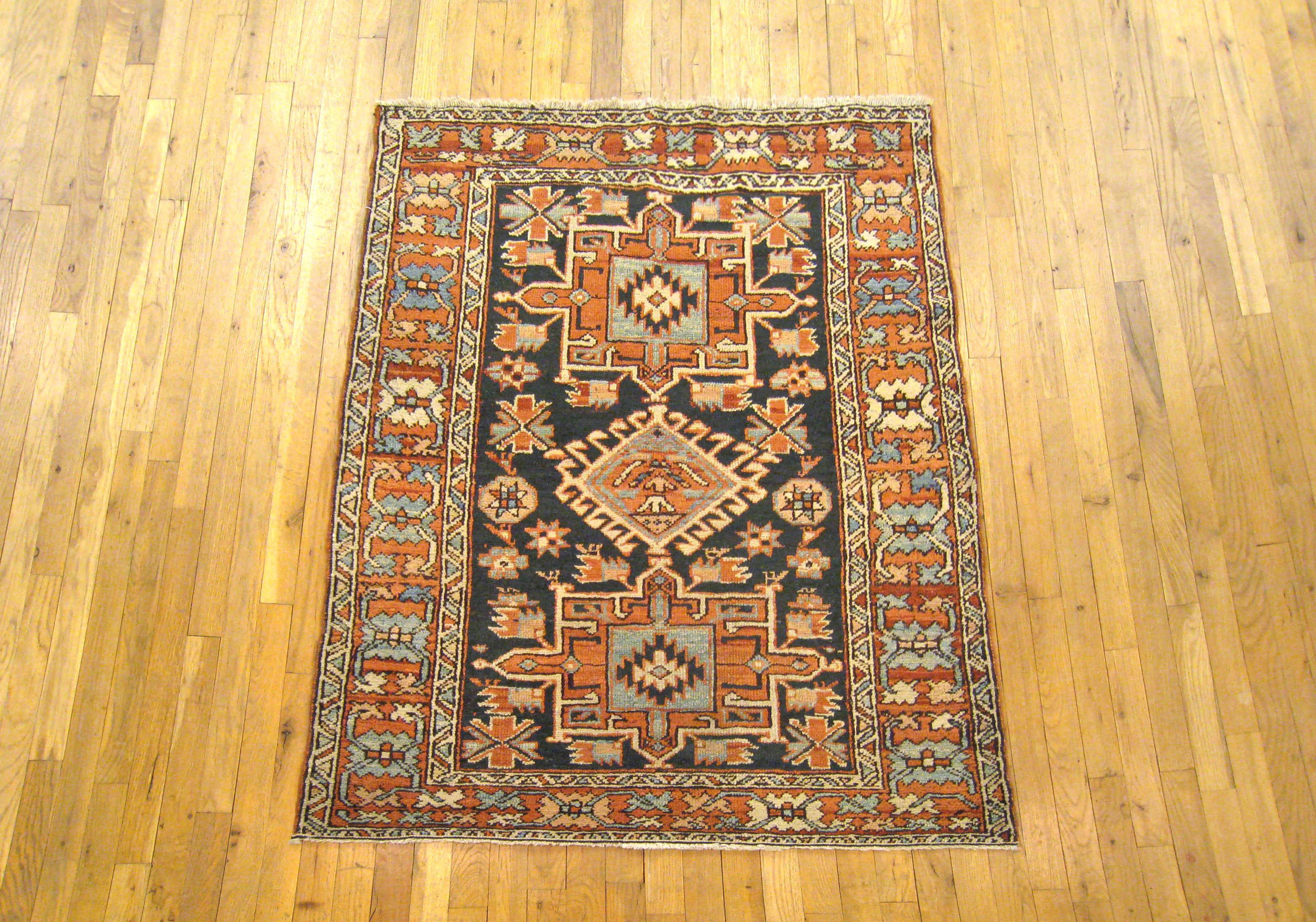 An antique Persian Heriz Karaja oriental rug, circa 1920, size 4'2 x 3'7. This handsome hand-knotted wool rug features a symmetrical series of central medallions on the uncluttered navy blue primary field. The field is enclosed within a vibrant red