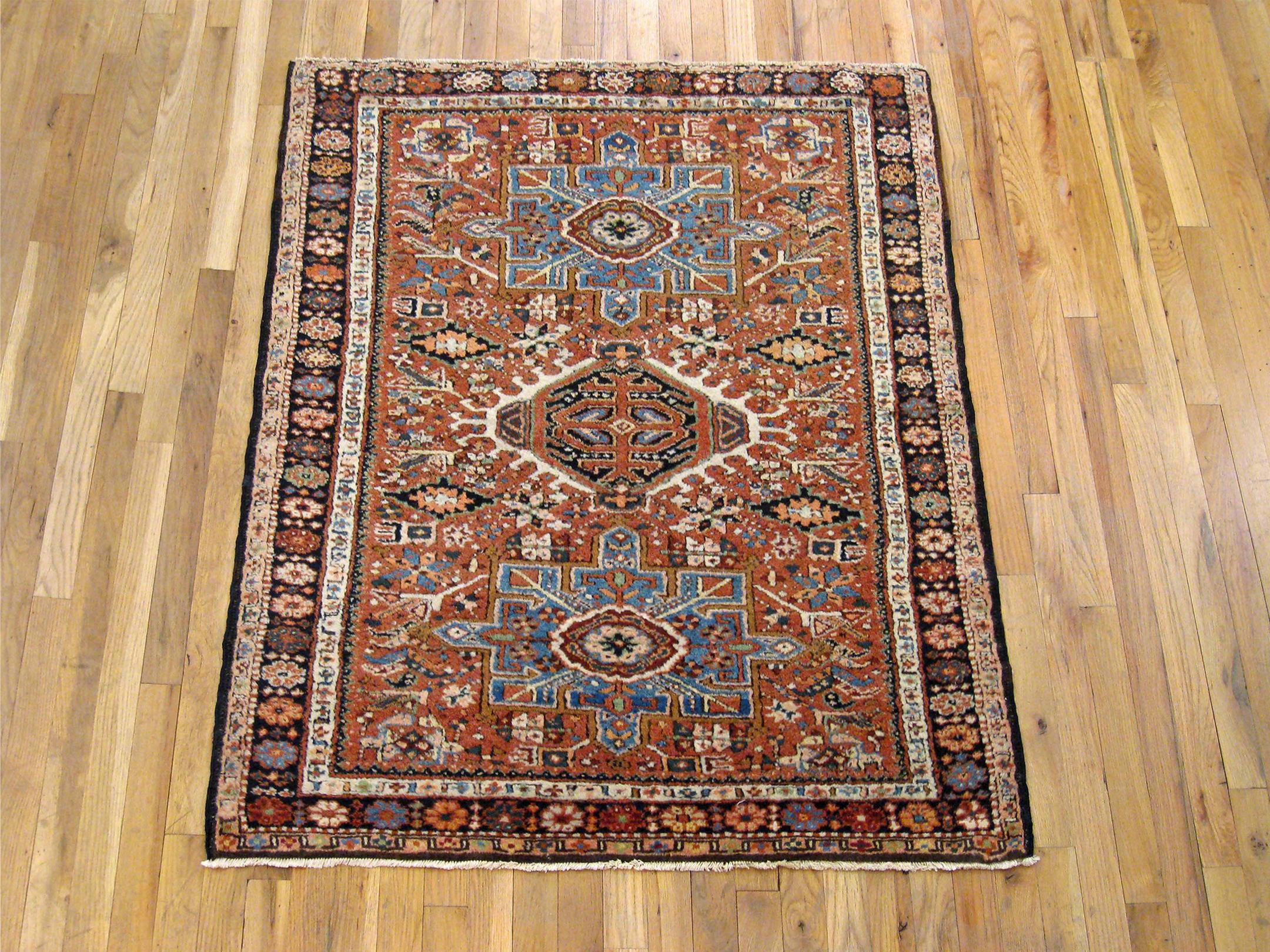 An antique Persian Heriz Karaja oriental rug, size 4'4 x 3'7, circa 1920. This handsome handwoven geometric rug features multiple medallions in the Classic red primary field. The central field is enclosed within a slim outer border in navy tones