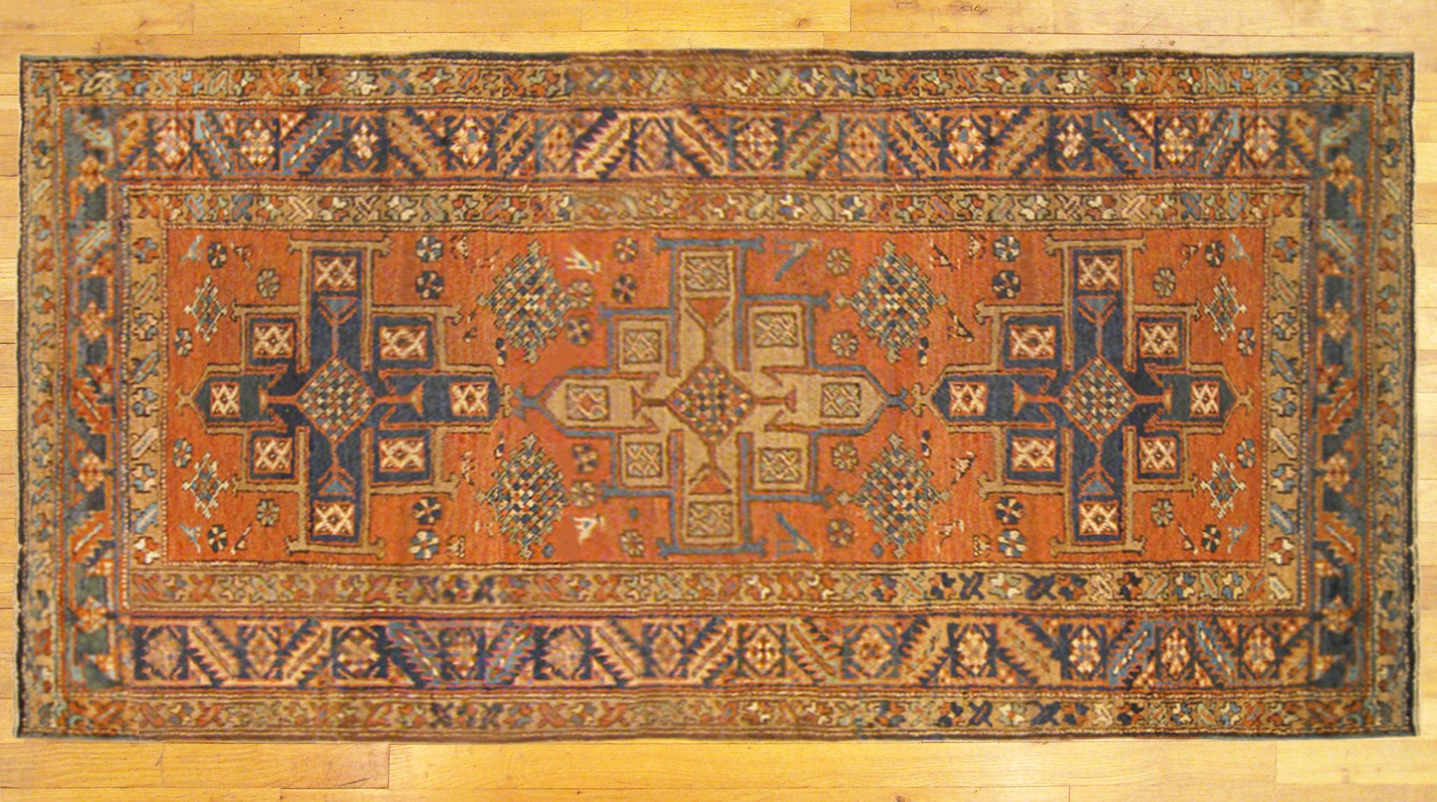 An antique Persian Heriz Karaja oriental rug, size 6'2 x 3'4, circa 1910. This handsome hand-woven geometric rug features multiple medallions in the rust-red primary field. The central field is enclosed within a blue outer border with motifs of