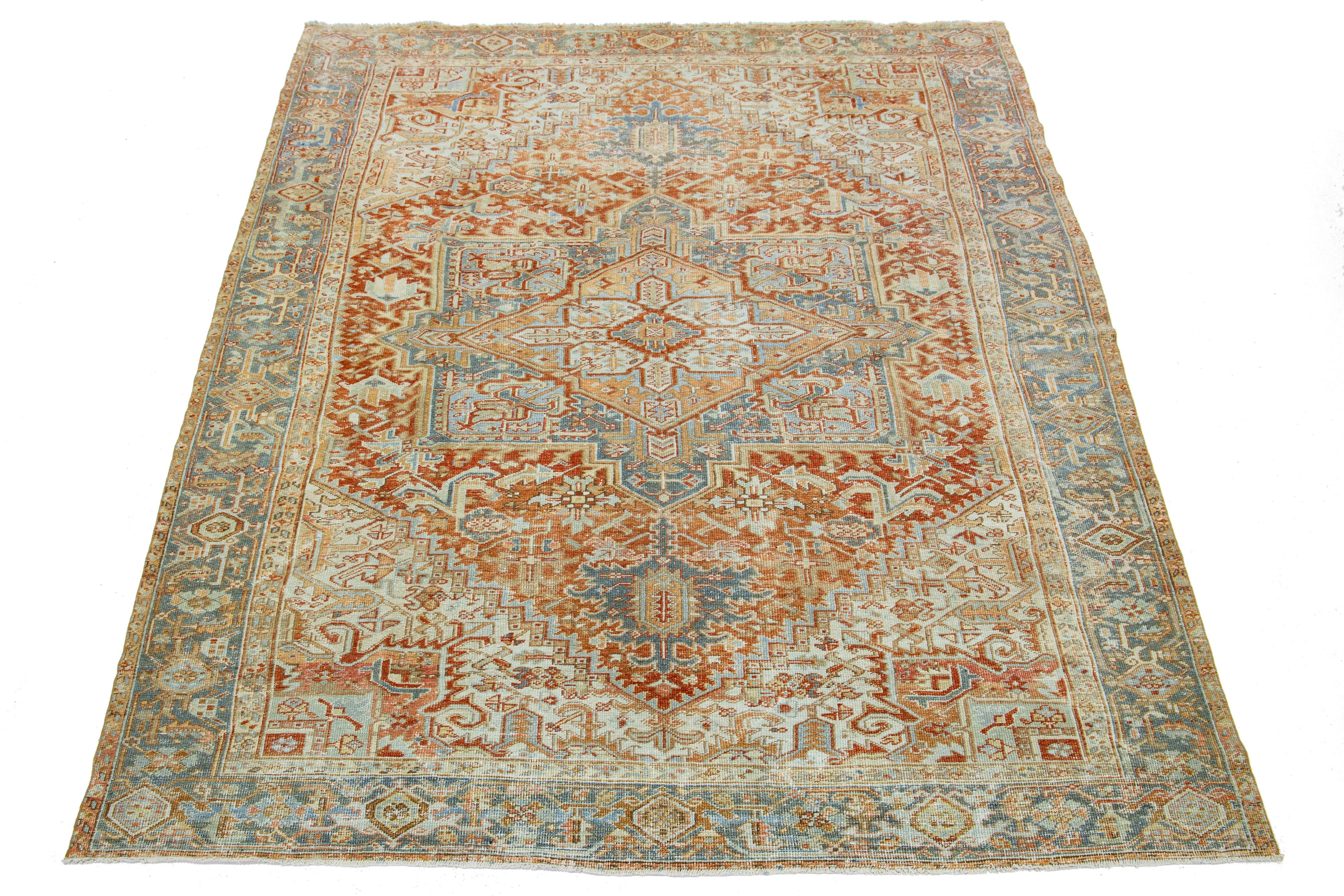 This antique Persian Heriz rug is crafted with hand-knotted wool. The rust-colored field features a captivating medallion pattern embellished with shades of blue, beige, and peach.

This rug measures 8' x 11'1