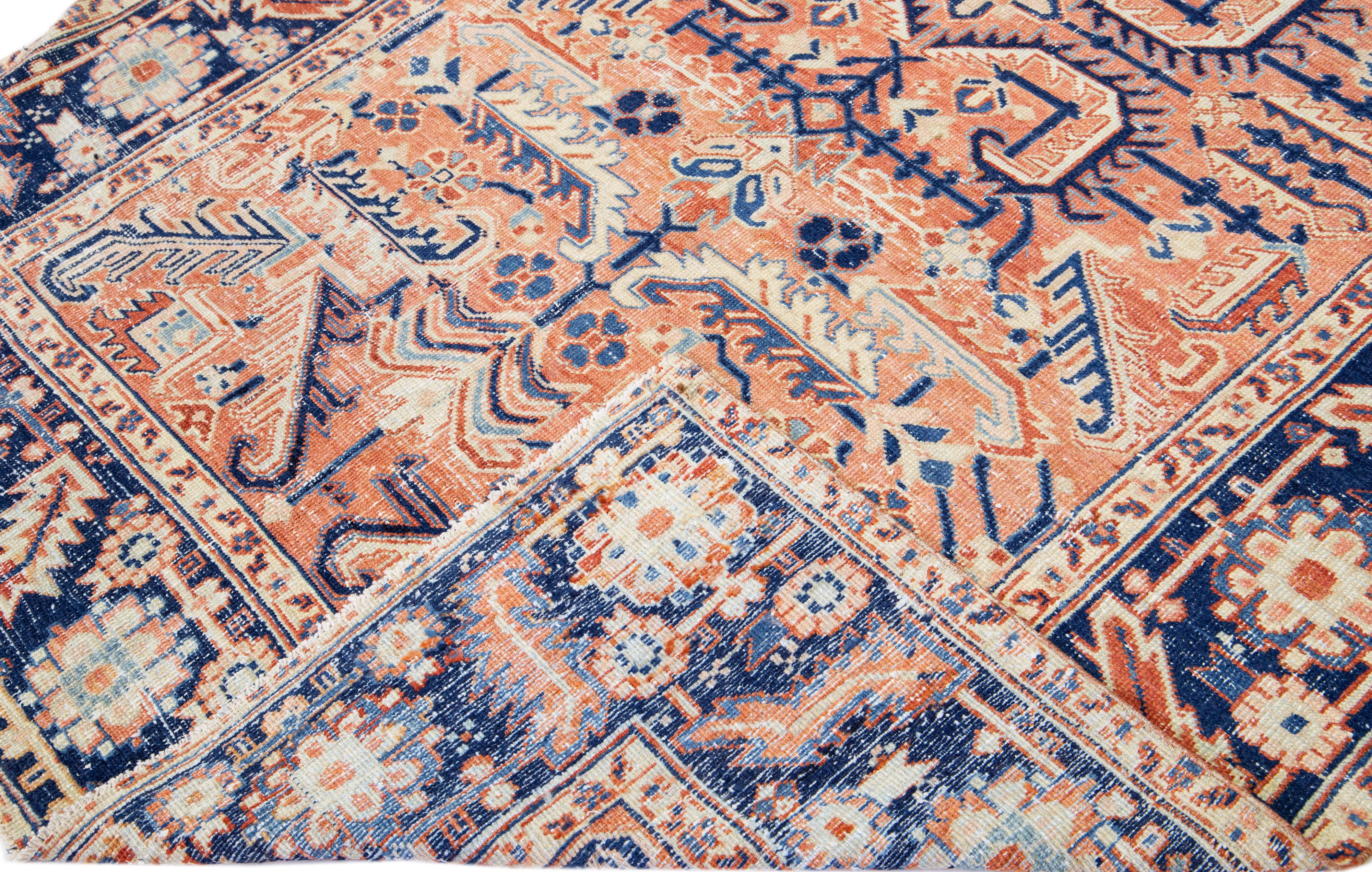 Beautiful antique Heriz hand-knotted wool rug with a peach color field. This Persian rug has a blue frame with beige and rust accents in a gorgeous all-over geometric medallion design.

This rug measures: 6'6