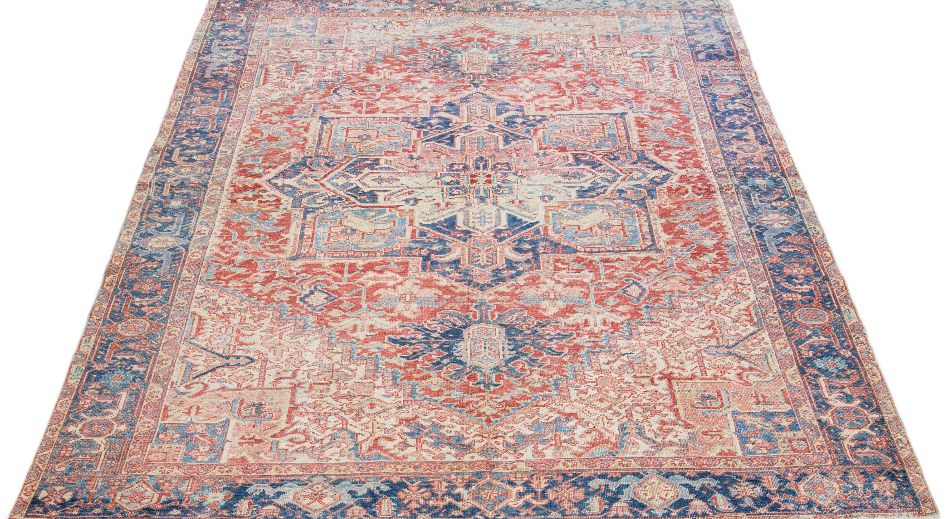 Beautiful antique Heriz hand-knotted wool rug with a peach color field. This Persian rug has a blue frame and rust accents in a gorgeous all-over geometric floral design.

This rug measures: 8'3