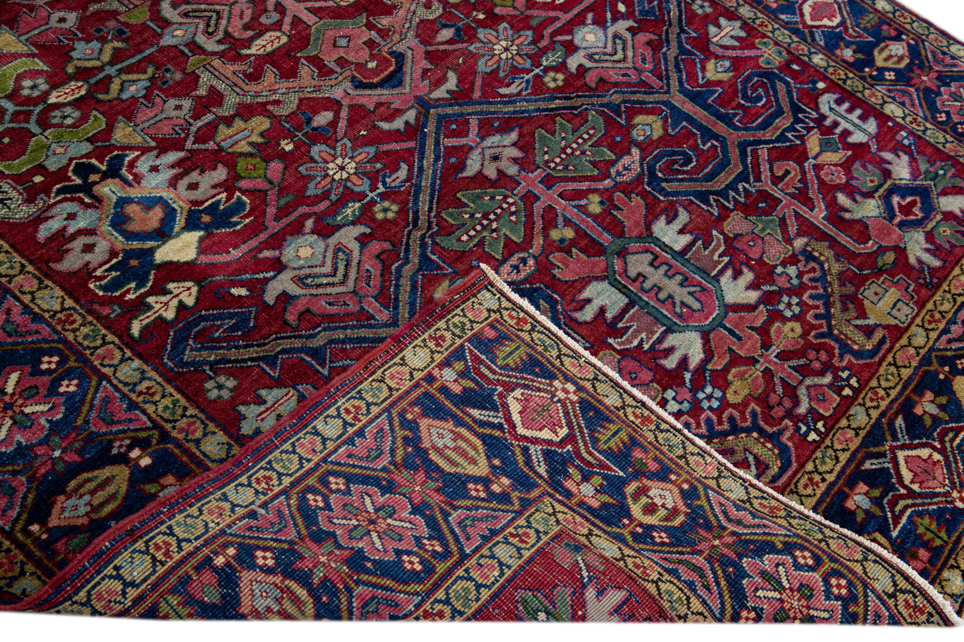 Beautiful antique Heriz hand-knotted wool rug with the red field. This Persian rug has a navy blue frame and accents of green, blue, and pink featuring a gorgeous allover floral design.

This rug measures: 6'3