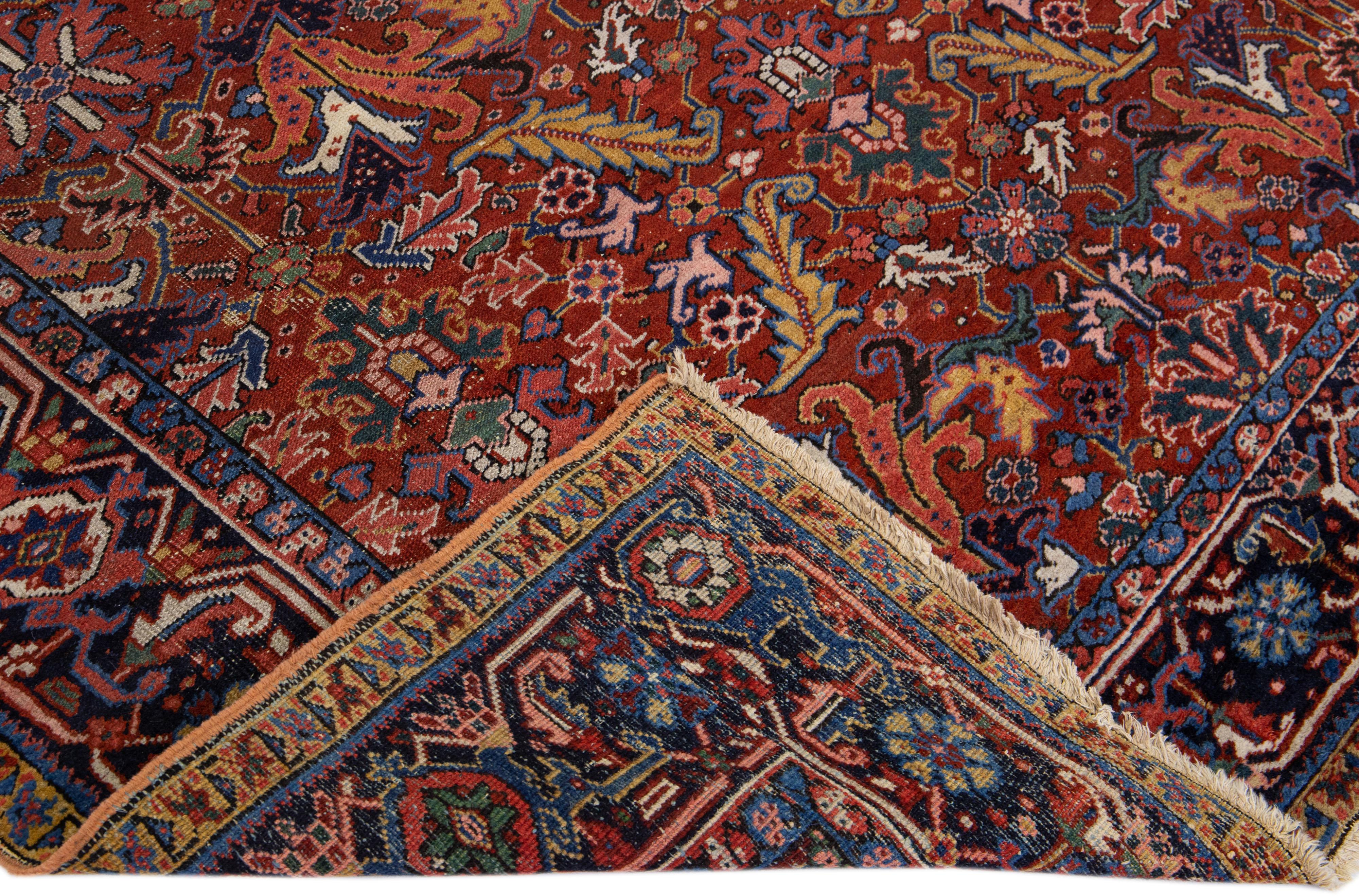 Beautiful antique Heriz hand-knotted wool rug with a red field. This Heriz rug has a navy blue frame and multi-color accents in a gorgeous all-over floral pattern design.

This rug measures: 7'3
