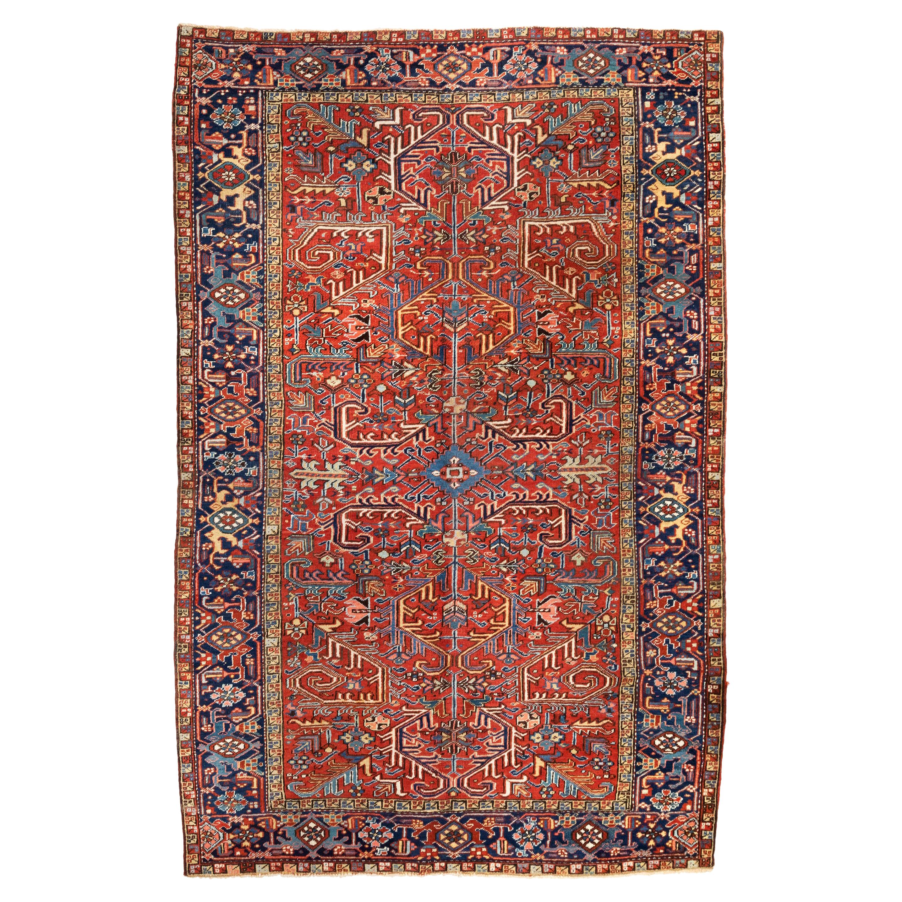 Ancien tapis persan Heriz, champ rouge bordé de bleu marine, vers les années 1930