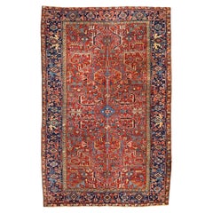 Ancien tapis persan Heriz, champ rouge bordé de bleu marine, vers les années 1930