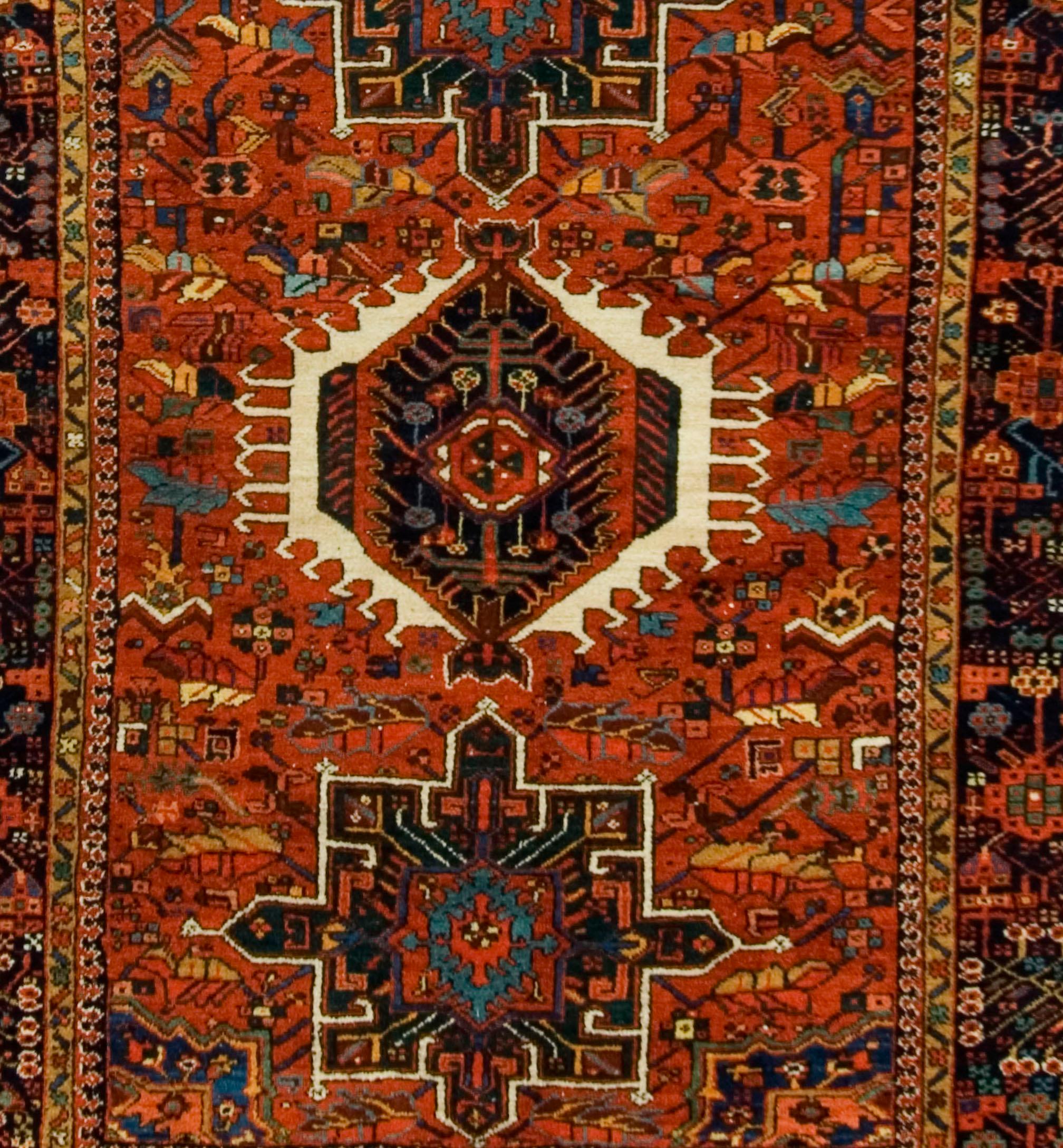 A lovely antique Persian Heriz rug measures 4'11 x 6'5 . The red ground with ivory, greens and soft blues create this small rug with a wonderful visual impact.