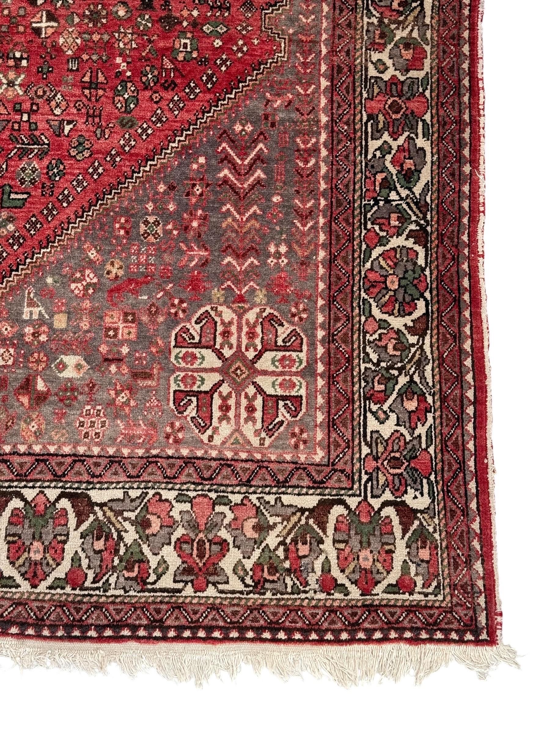 This striking antique Persian Heriz rug features a classic geometric medallion design rendered in deep red and soft grey tones, with intricate motifs that reflect the time-honored artistry of Persian weaving. Entirely handwoven in pure wool on a