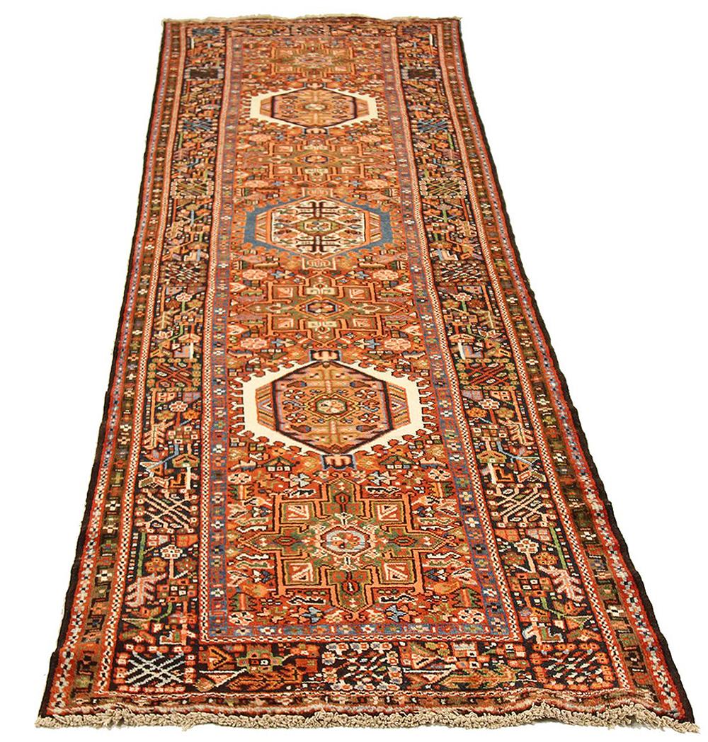 Antique Persian runner rug handwoven from the finest sheep’s wool and colored with all-natural vegetable dyes that are safe for humans and pets. It’s a traditional Heriz design featuring a lovely field filled with nature details all-over highlighted