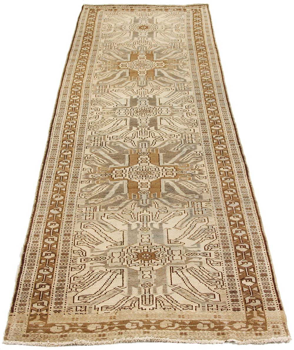 Antique Persian runner rug handwoven from the finest sheep’s wool and colored with all-natural vegetable dyes that are safe for humans and pets. It’s a traditional Heriz design featuring a lovely ivory field covered with brown and gray tribal