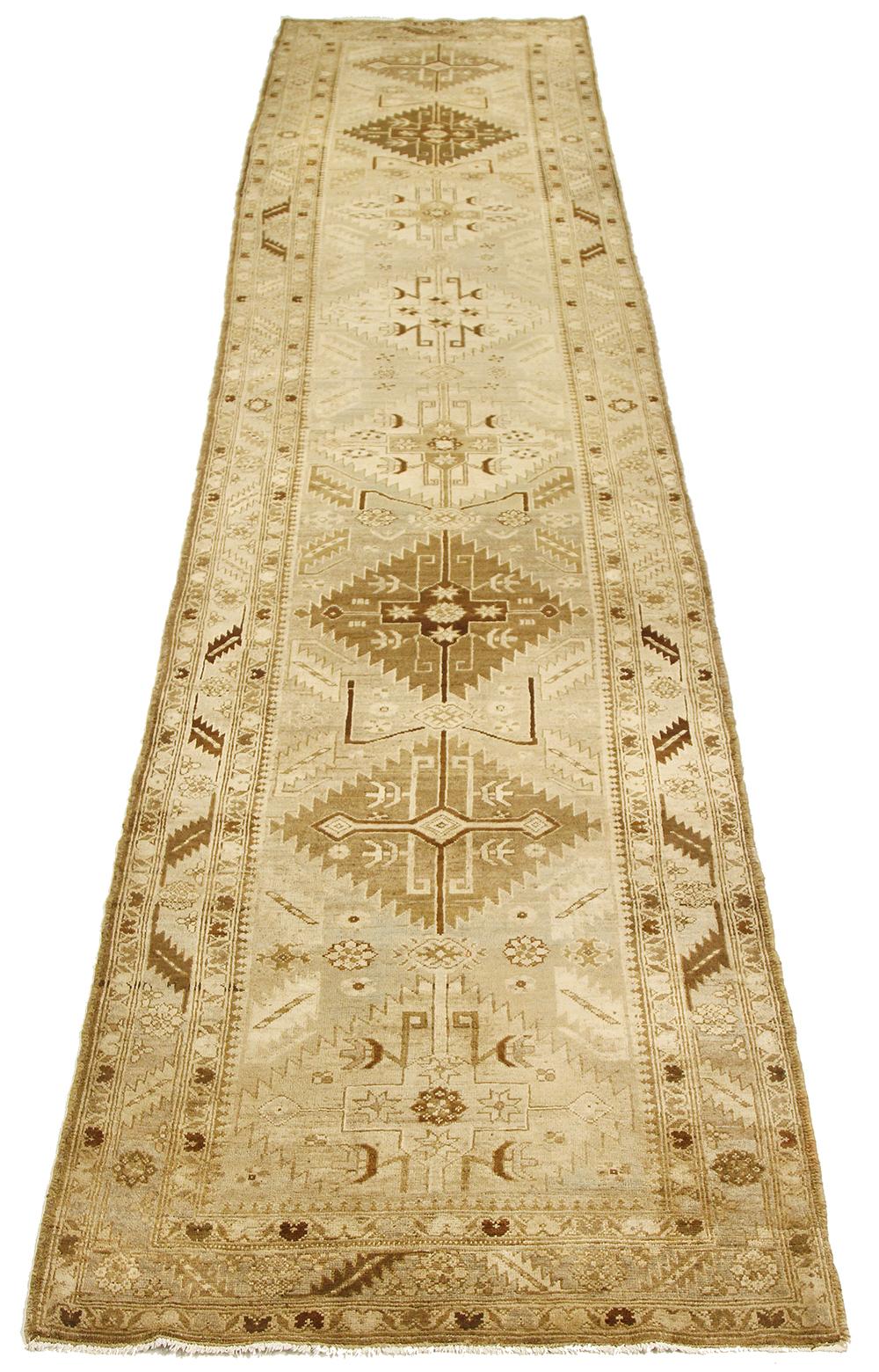 Antique Persian runner rug handwoven from the finest sheep’s wool and colored with all-natural vegetable dyes that are safe for humans and pets. It’s a traditional Heriz design featuring a lovely ivory field covered with brown tribal details. It’s a