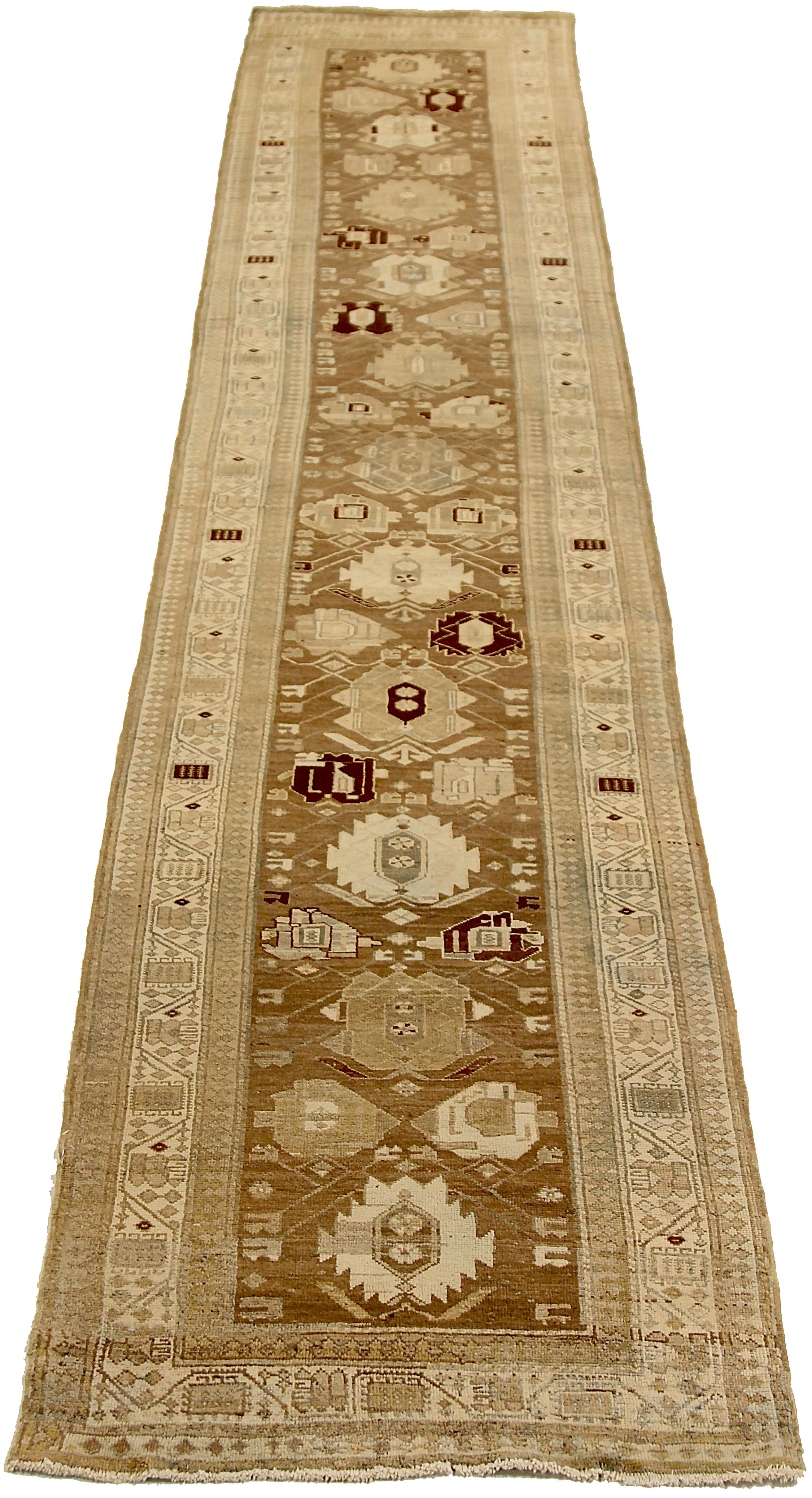 Antique Persian runner rug handwoven from the finest sheep’s wool and colored with all-natural vegetable dyes that are safe for humans and pets. It’s a traditional Heriz design featuring a lovely brown field covered with ivory floral and tribal
