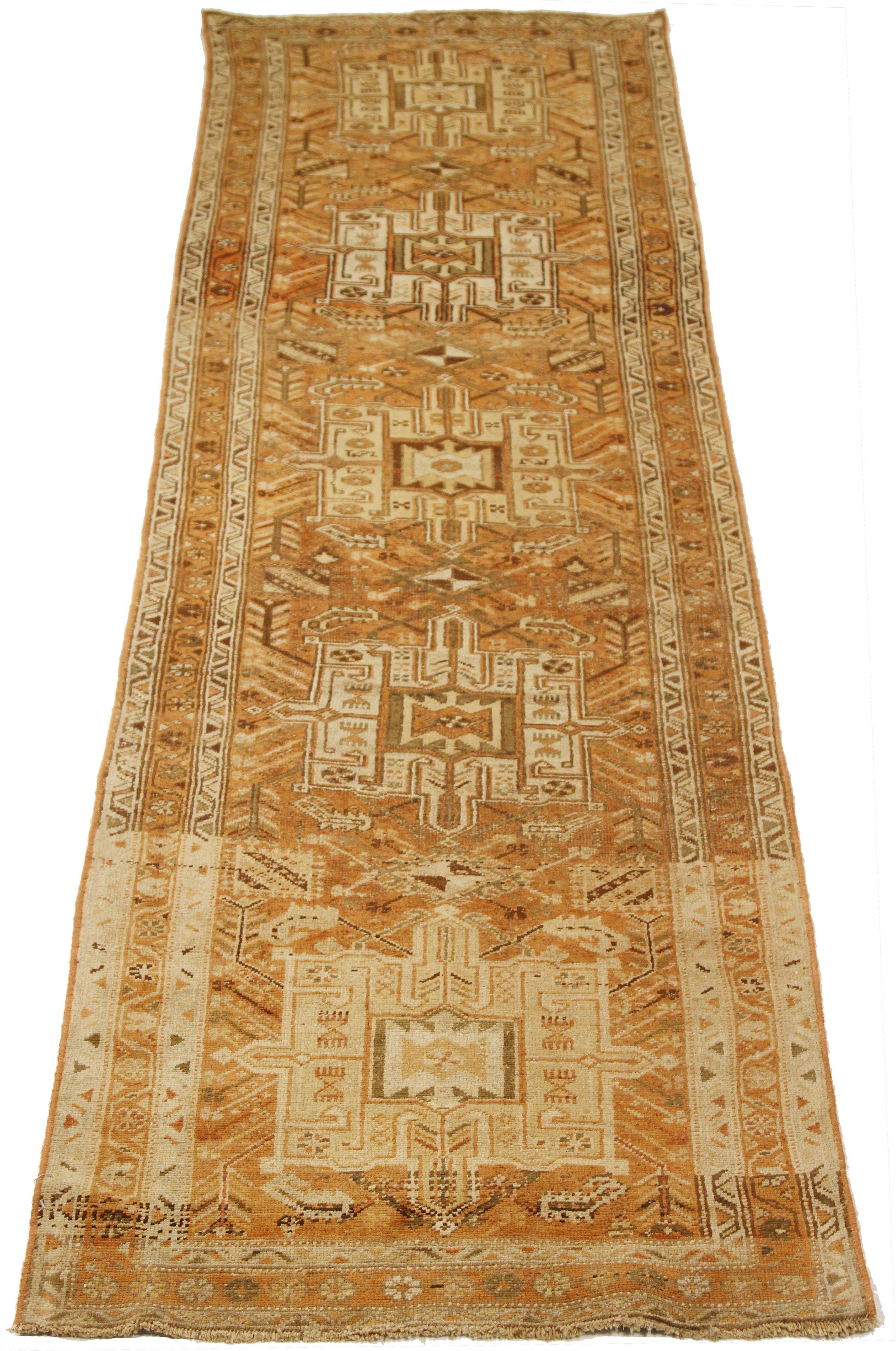Antique Persian runner rug handwoven from the finest sheep’s wool and colored with all-natural vegetable dyes that are safe for humans and pets. It’s a traditional Heriz design featuring a lovely field covered with ivory and brown tribal design