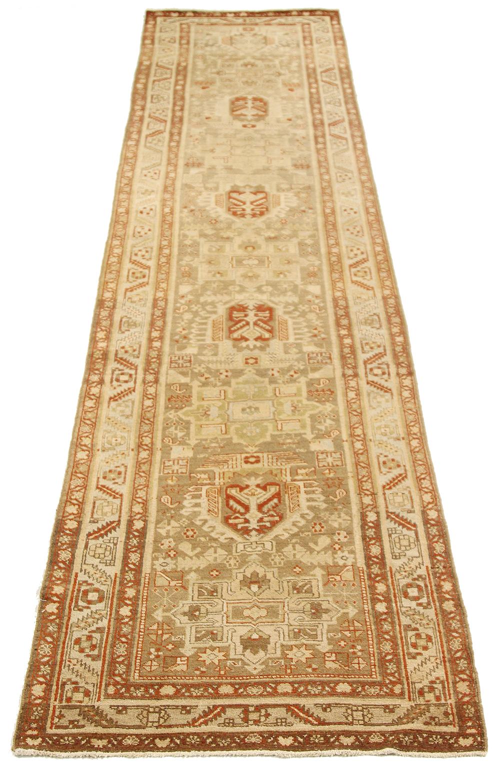 Antique Persian runner rug handwoven from the finest sheep’s wool and colored with all-natural vegetable dyes that are safe for humans and pets. It’s a traditional Heriz design featuring a lovely field covered with ivory and red tribal details. It’s
