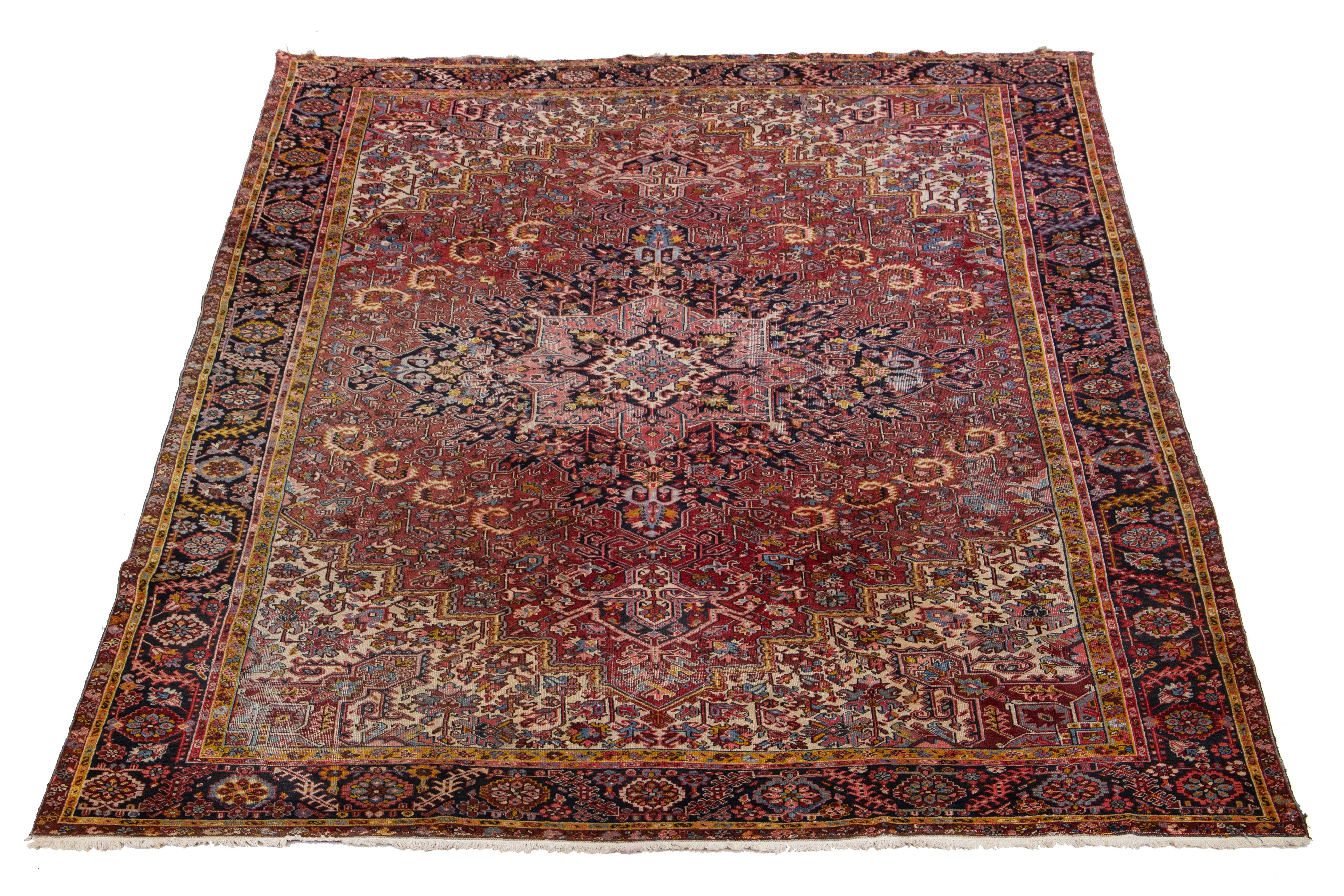 This antique Persian Heriz rug is made with hand-knotted wool. The red field showcases a captivating tribal pattern with multicolor shades.

This rug measures 11'2