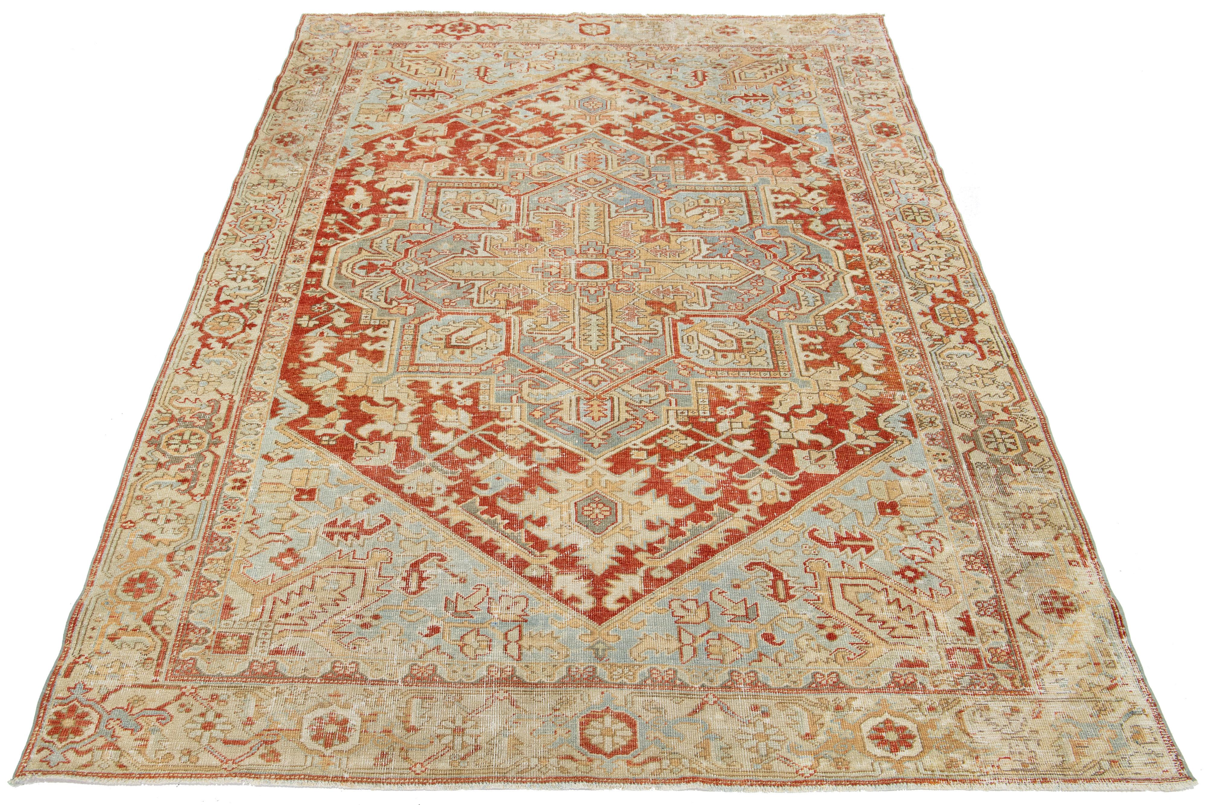 Ce tapis persan antique en laine Heriz présente un motif bleu et beige envoûtant, élégamment mis en valeur sur un fond rouille riche et profond.

Ce tapis mesure 6'10