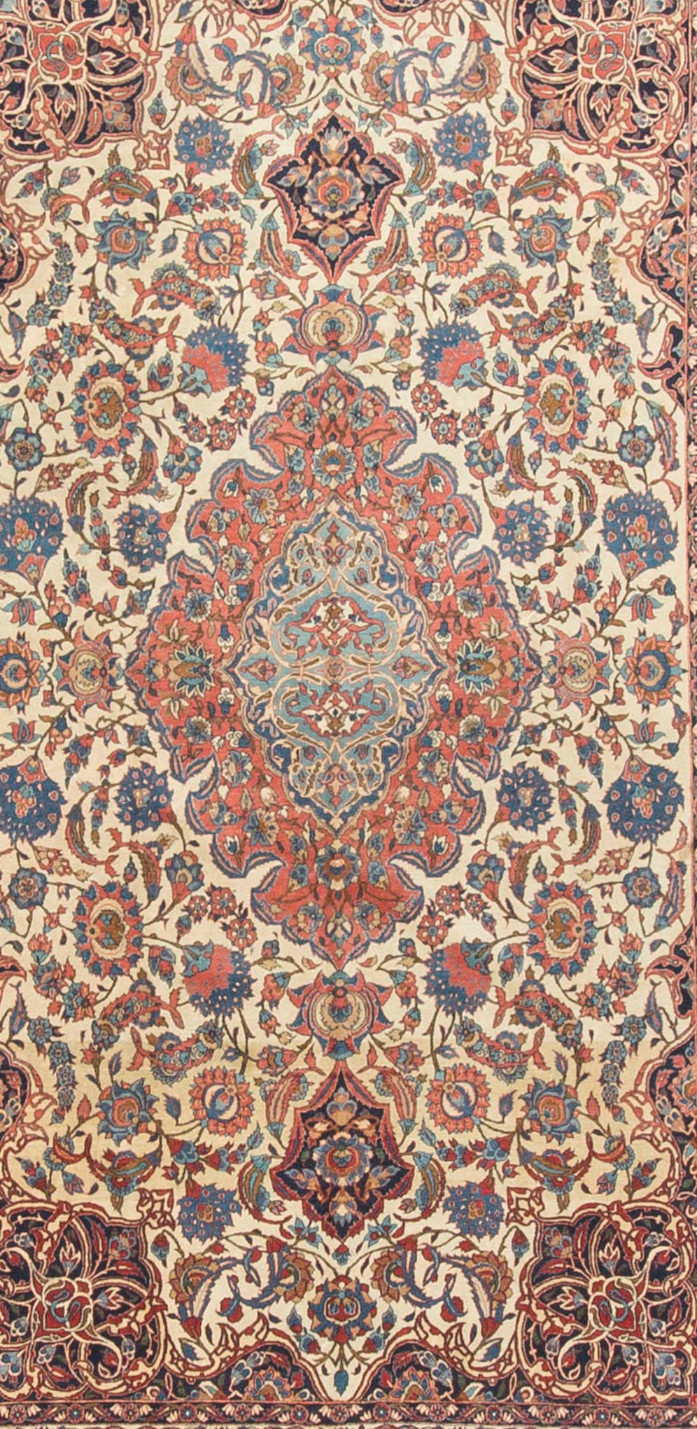 Antiker persischer Isfahan-Teppich mit einem zentralen Medaillon in sanften Blautönen, umgeben von einem floralen Muster in zarten Rottönen, umgeben von einem elfenbeinfarbenen Feld mit Eckzwickeln in tiefen Blautönen. Die Hauptbordüre und zwei