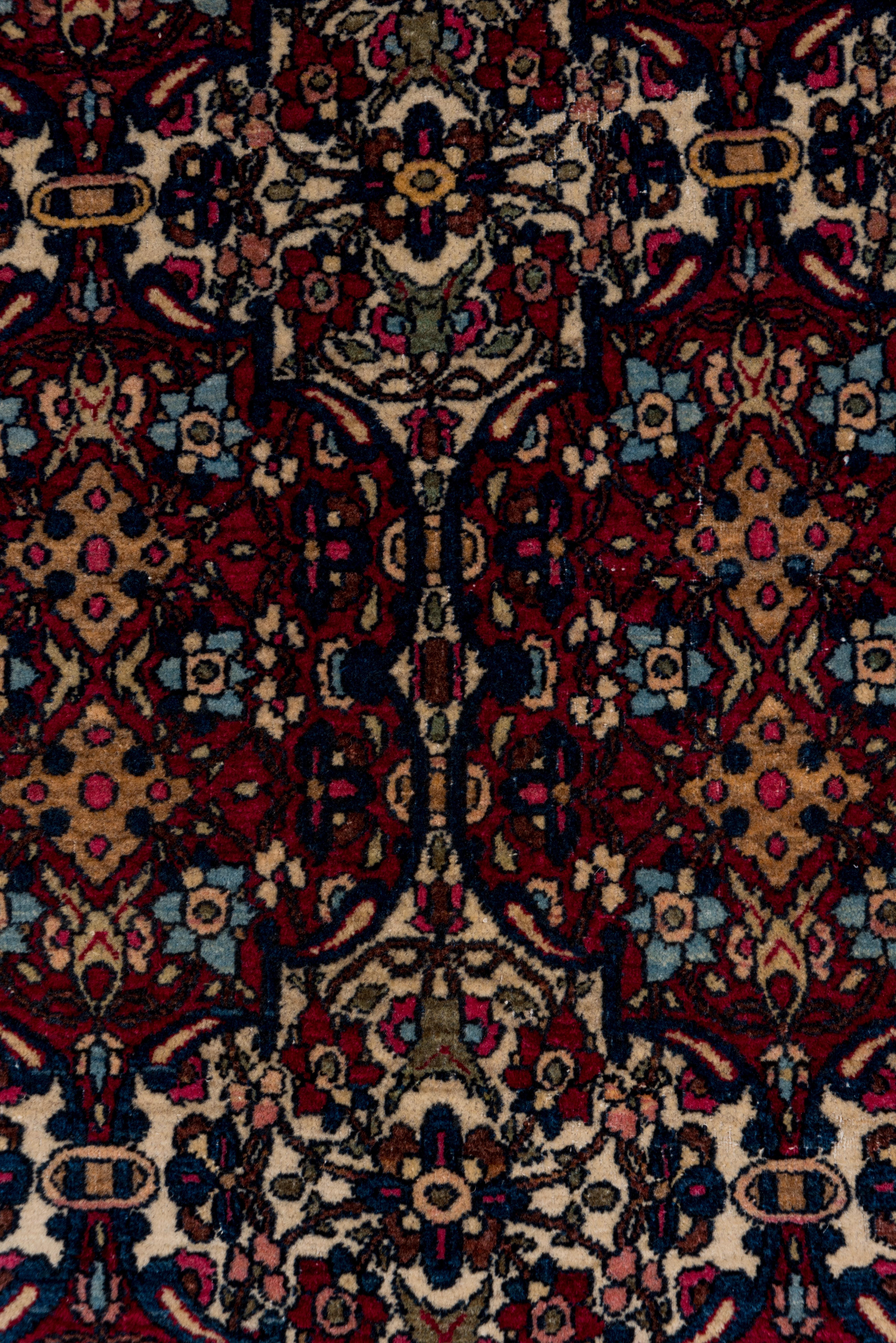 El campo de color marfil y rojo oscuro presenta una cartela ojival de dos por tres en rojo mora. La cenefa de color beige camel presenta rosetas y palmetas de pétalos de perfil en una doble cadena de viñedos. Base de algodón, tejido urbano fino.