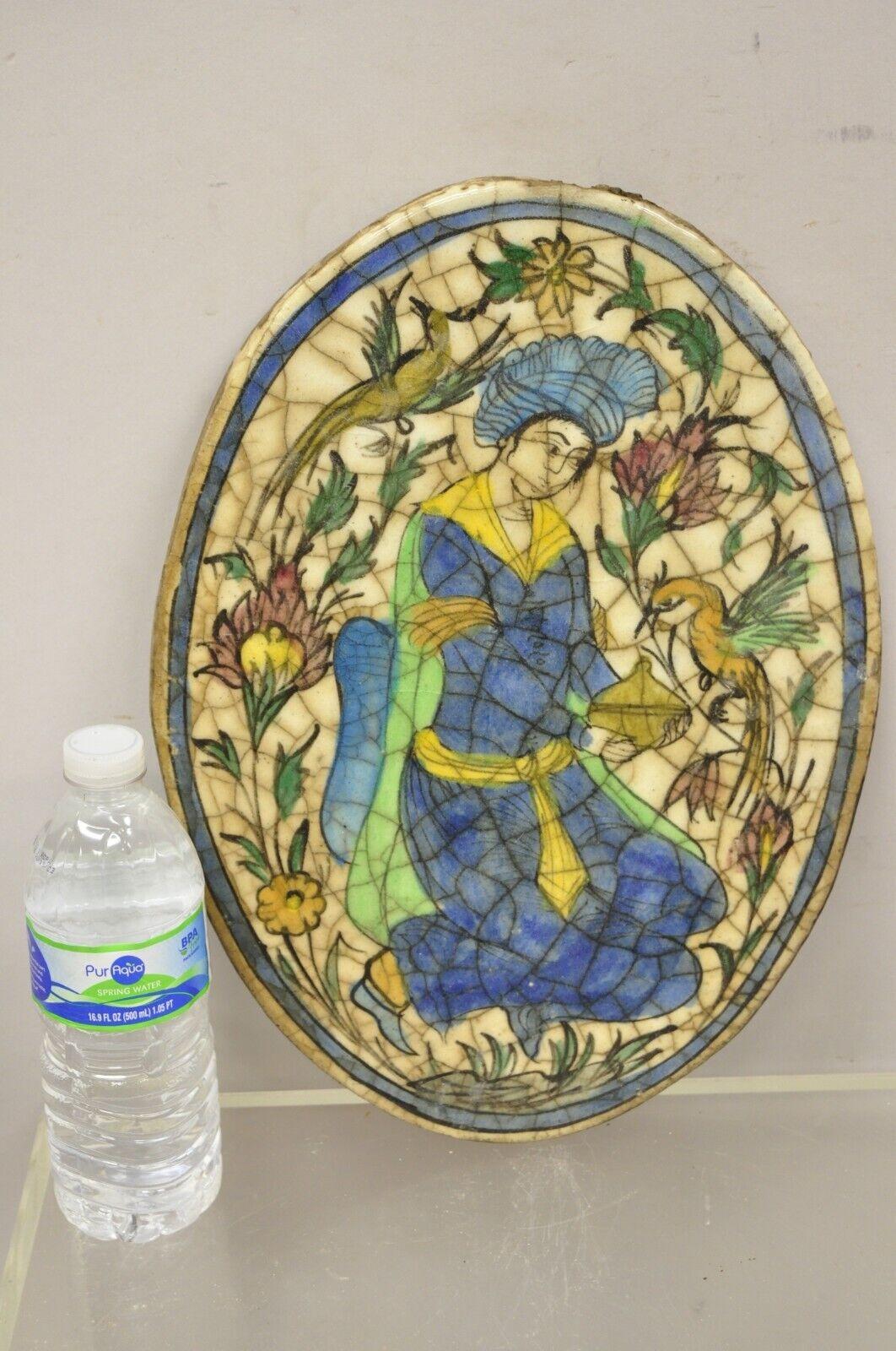 Antique Persian Iznik Qajar Style Ceramic Pottery Oval Tile Figure in Blue Garb with Bird C3. Item features original crackle glazed finish, heavy ceramic pottery construction, very impressive detail, wonderful style and form. Great to mount as wall