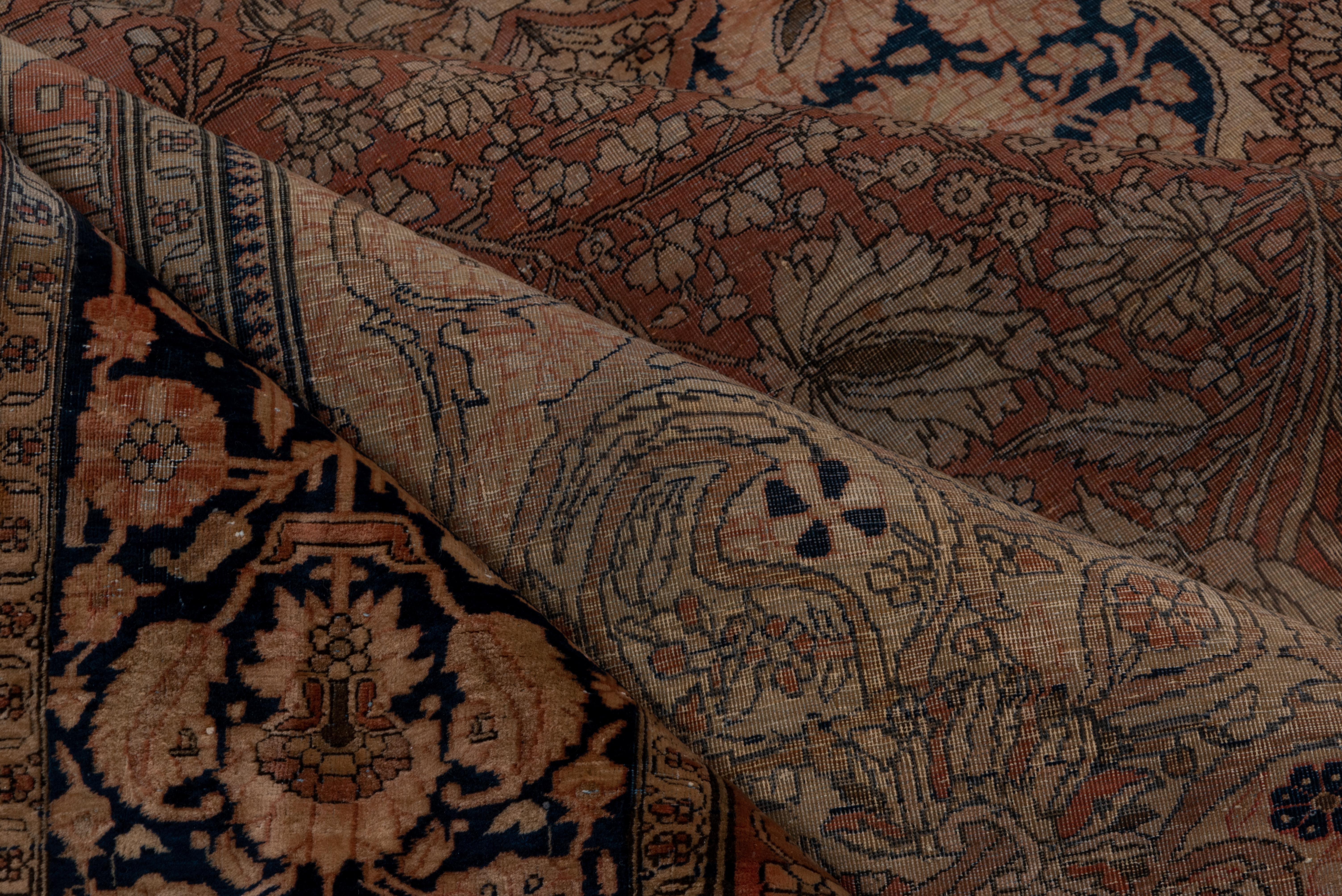 This finely woven central Persian town carpet with a particularly velvety pile was woven during the period of, and possibly by the famous Mohtasham workshop. The rust palmette and vine filled field presents a scalloped lozenge navy medallion with