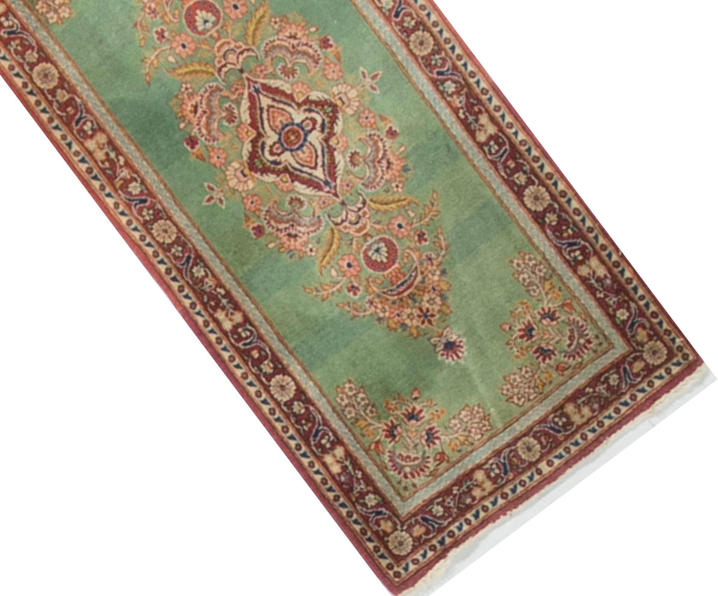 A lovely small antique Kashan rug. The central medallion siting on a soft green field with four corner spandrels matching the central pattern. The darker red border enhances the overall look to this small but detailed rug.