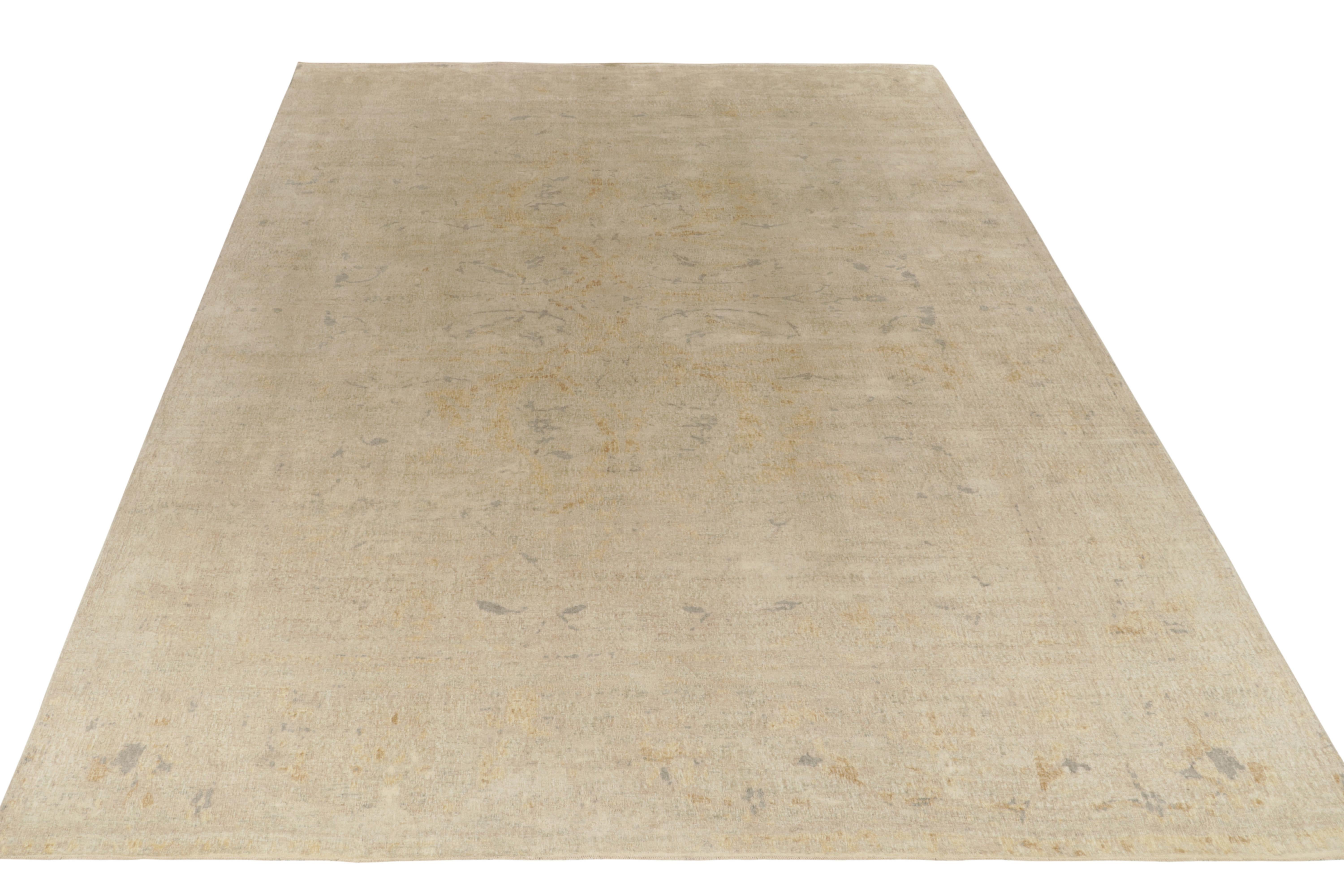 Hand knotted in quality wool, this 12x16 modern rug enjoys muted classic inspirations in tones of beige with gold and silver-gray accents. Seldom seen together in this subtle adaptation of a transitional style, an atypical colorway further