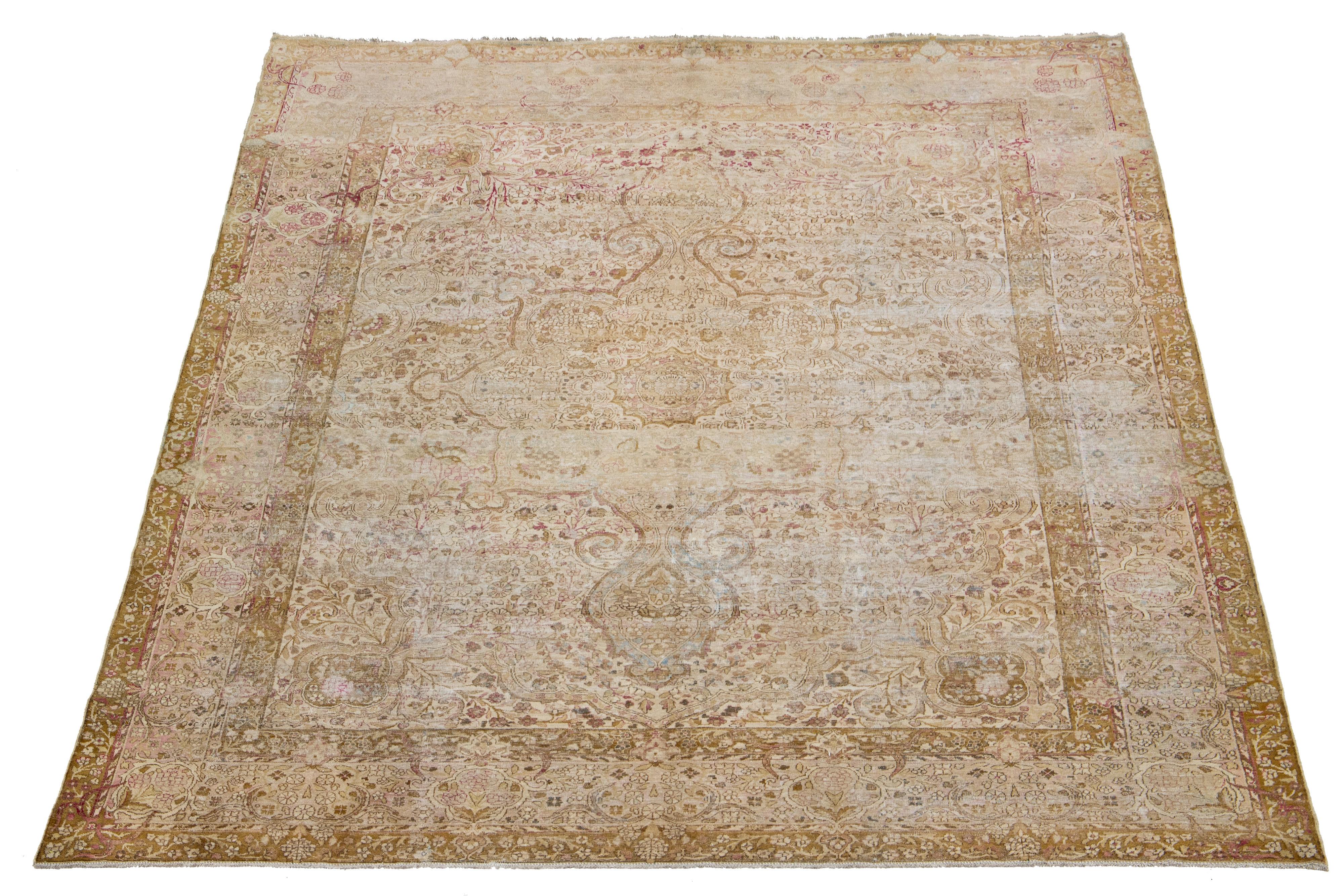 Magnifique tapis ancien en laine nouée à la main de Kerman, avec un champ beige. Ce tapis persan présente des accents bleus, rouges et havane dans un superbe motif botanique en médaillon. 

Ce tapis mesure 9'10
