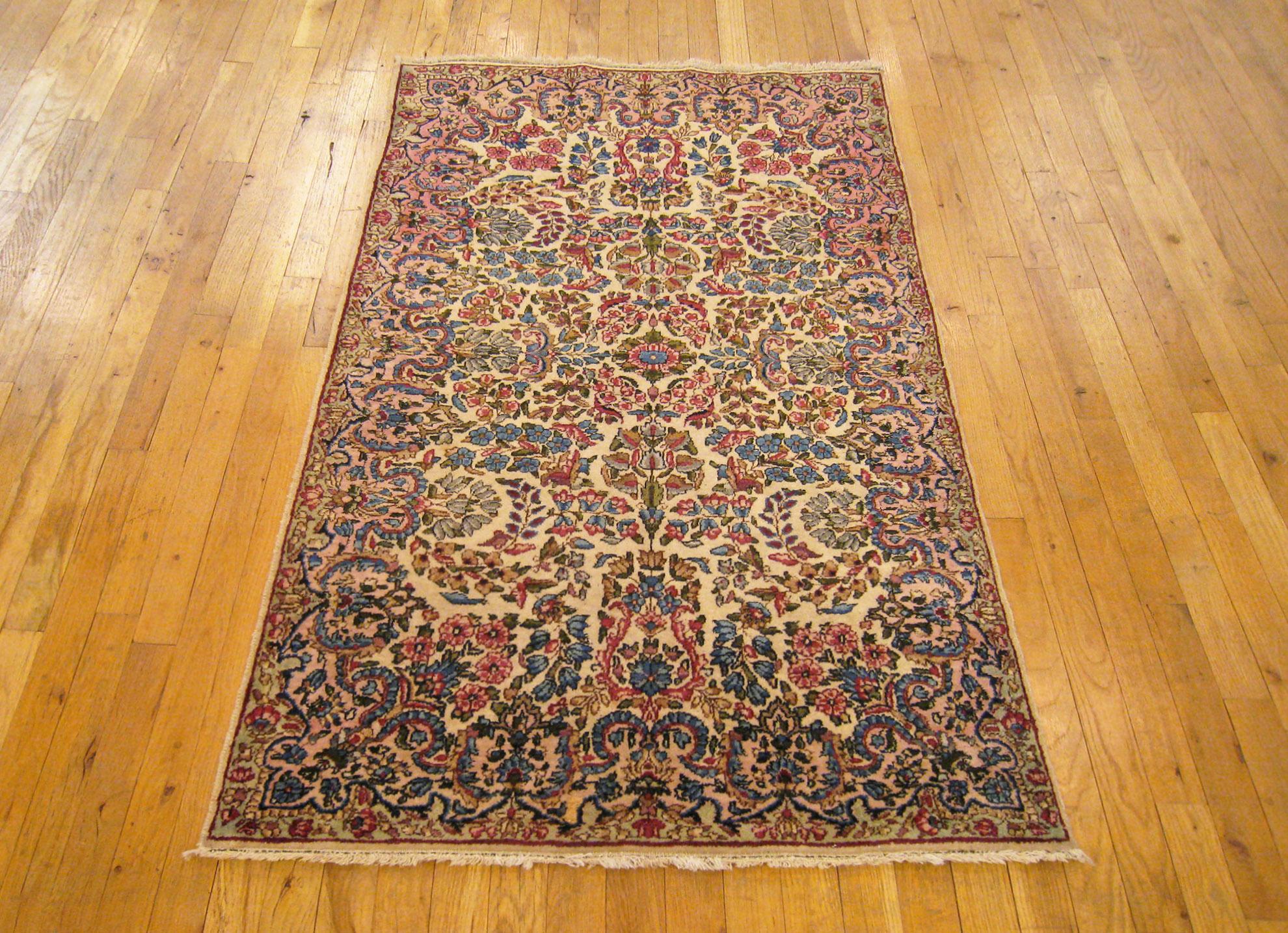 An antique Persian Kerman oriental rug, size 5' x 3', circa 1920. This delightful small carpet features an ivory central field covered with a variety of floral elements, which seamlessly blend into the light blue outer border. Hand-woven with wool,