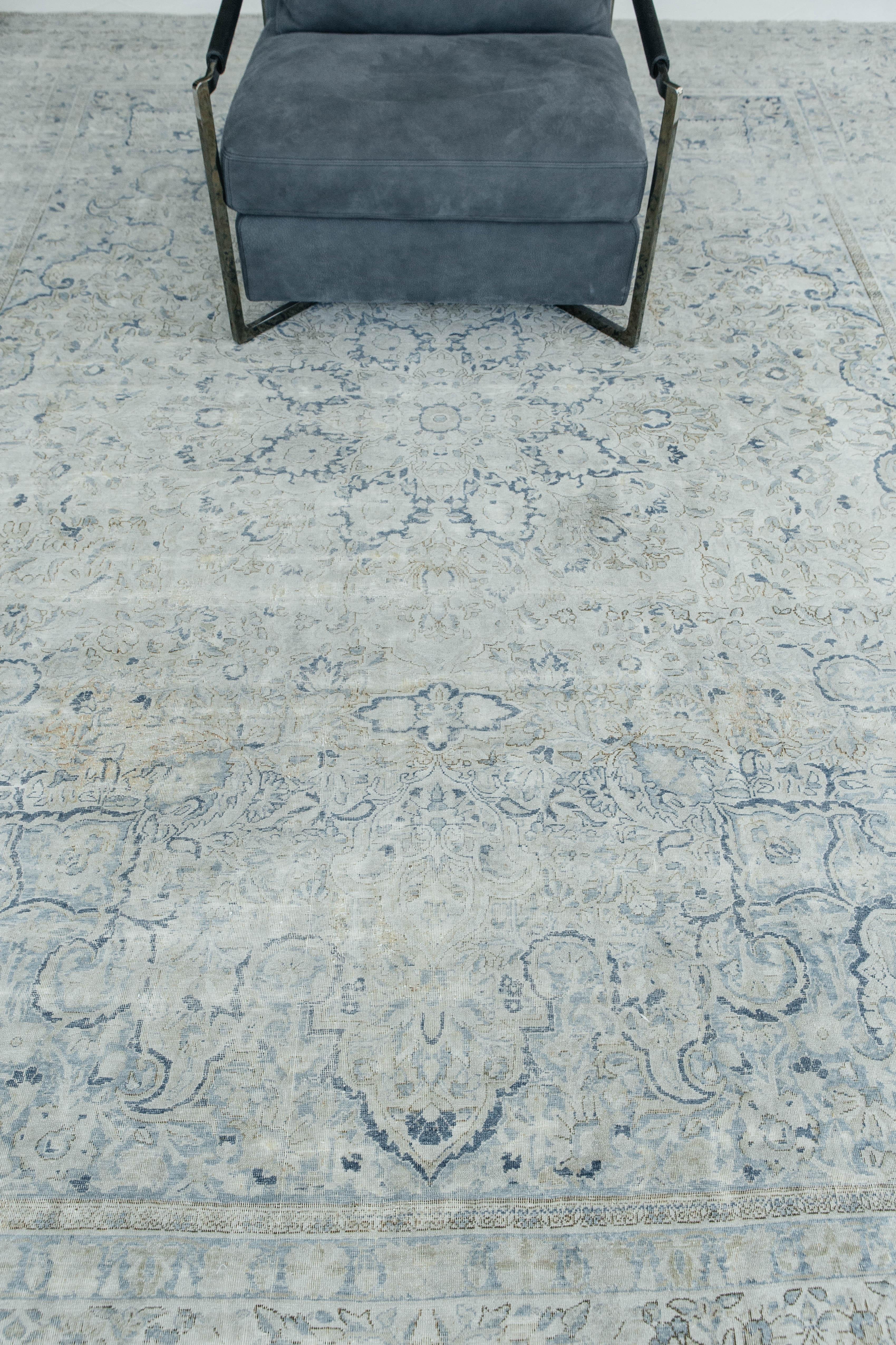 An antique Persian Kermanshah rug with neutral hues and beautiful blue accents. Kermanshah carpets are a unique and appealing style of antique Persian rugs, characterized by their distinct tribal aesthetic. This piece's geometric structure as well
