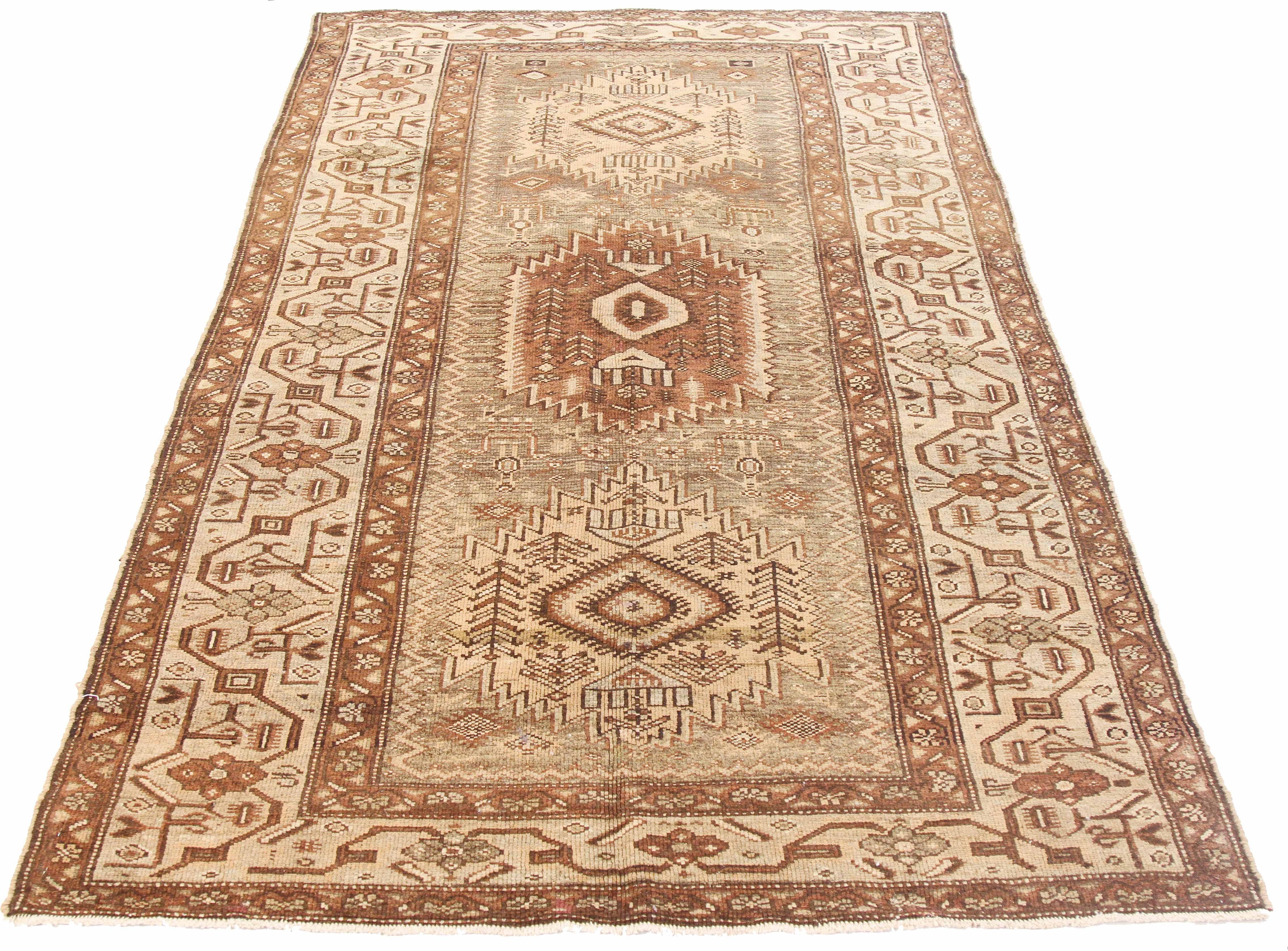 Antique Persian rug handwoven from the finest sheep’s wool and colored with all-natural vegetable dyes that are safe for humans and pets. It’s a traditional Khamseh design featuring large brown and beige tribal central medallions on an ivory field.