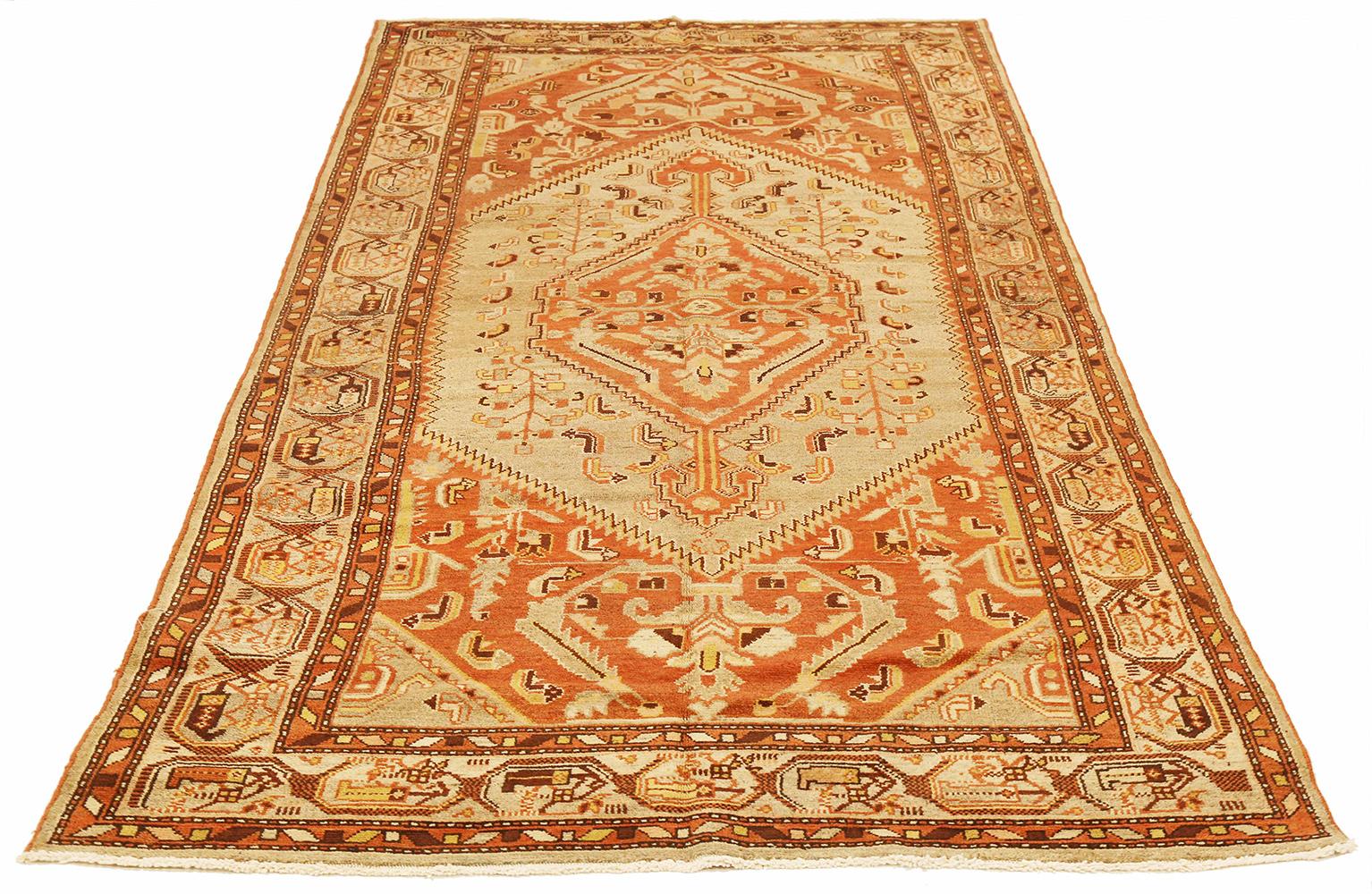 Antique Persian rug handwoven from the finest sheep’s wool and colored with all-natural vegetable dyes that are safe for humans and pets. It’s a traditional Khamseh design featuring a gorgeous mix of brown and ivory tribal details on an orange