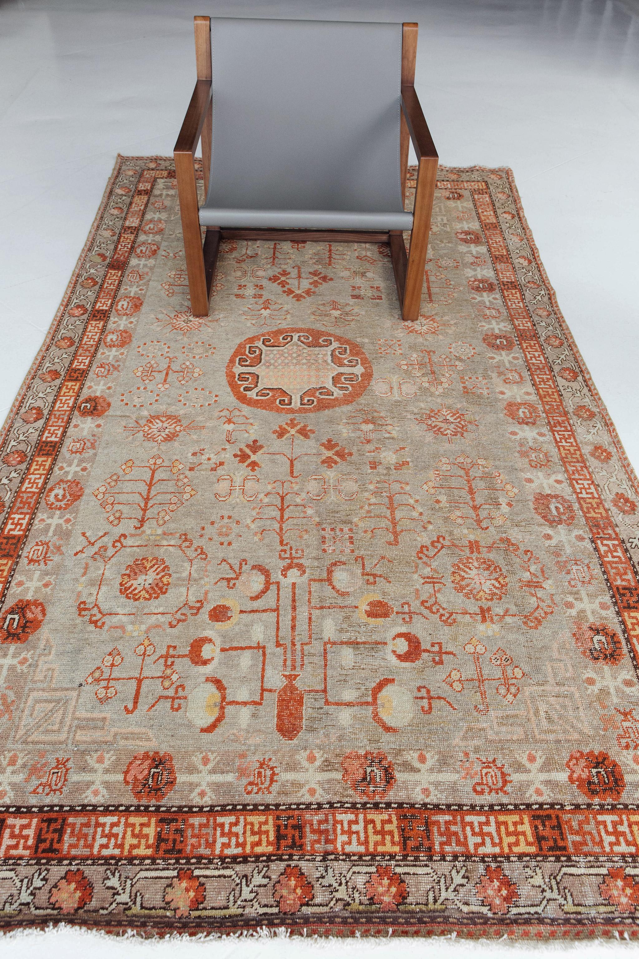 An epitome of history, character and culture, antique Khotan rugs add richness to a room. This rug features geometric and abstract drawings with rich colors and a small circular medallion. A subtle green and red are the prominent color pallets on