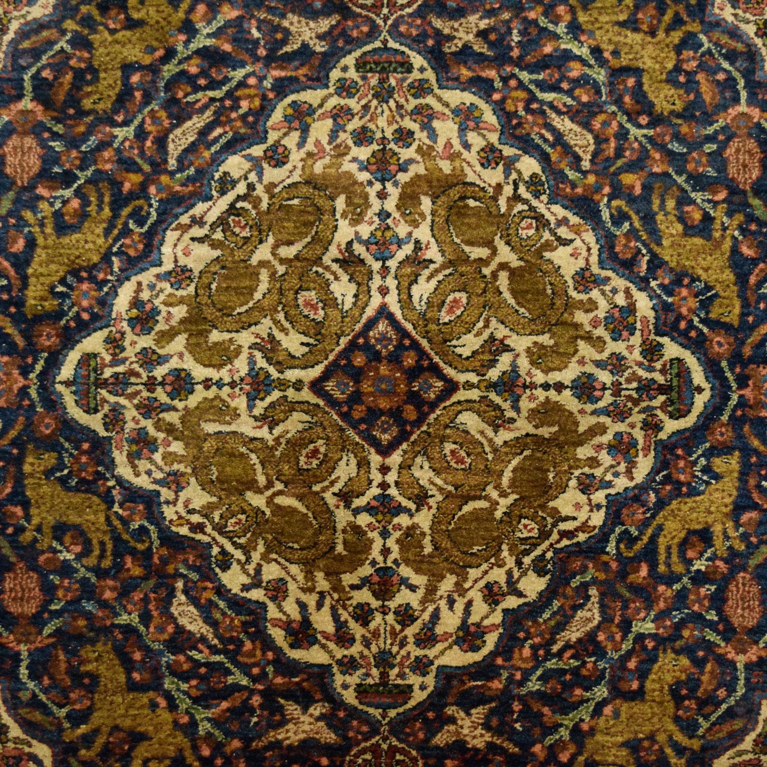 This antique Persian Khoy carpet, circa 1900, in cream, green, and indigo measures 4’9” x 7’10”. Featuring a traditional Persian hand-knotted weave, this carpet exhibits a soft and plush pile and durable foundation. The pile consists of hand-spun