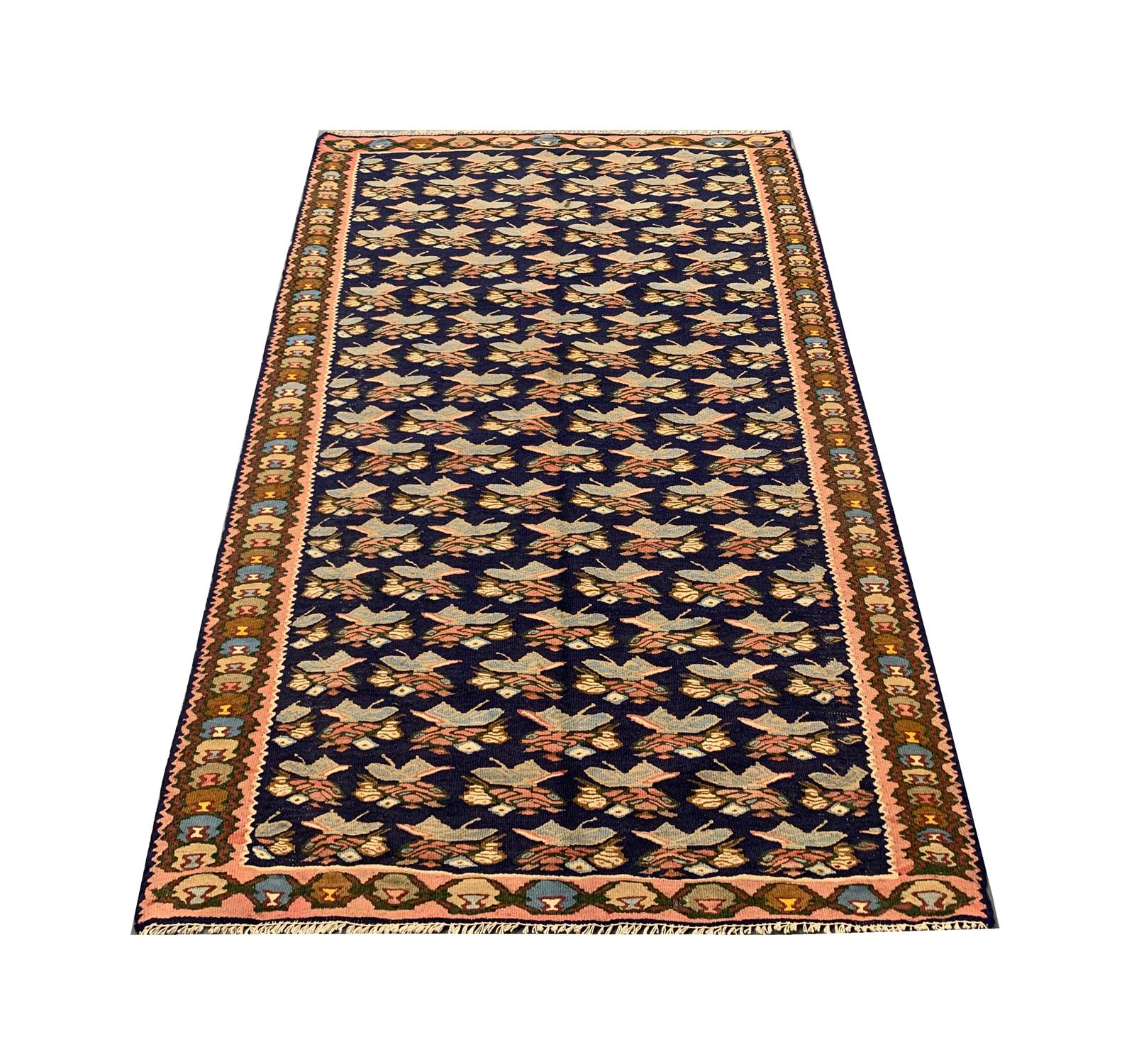 Crafted with meticulous hand-knotting, boasts a fusion of tradition and timeless elegance. The weave exudes a sense of authenticity, setting it apart as a truly exceptional find. The pattern is woven on a terracotta rust-blue background and features