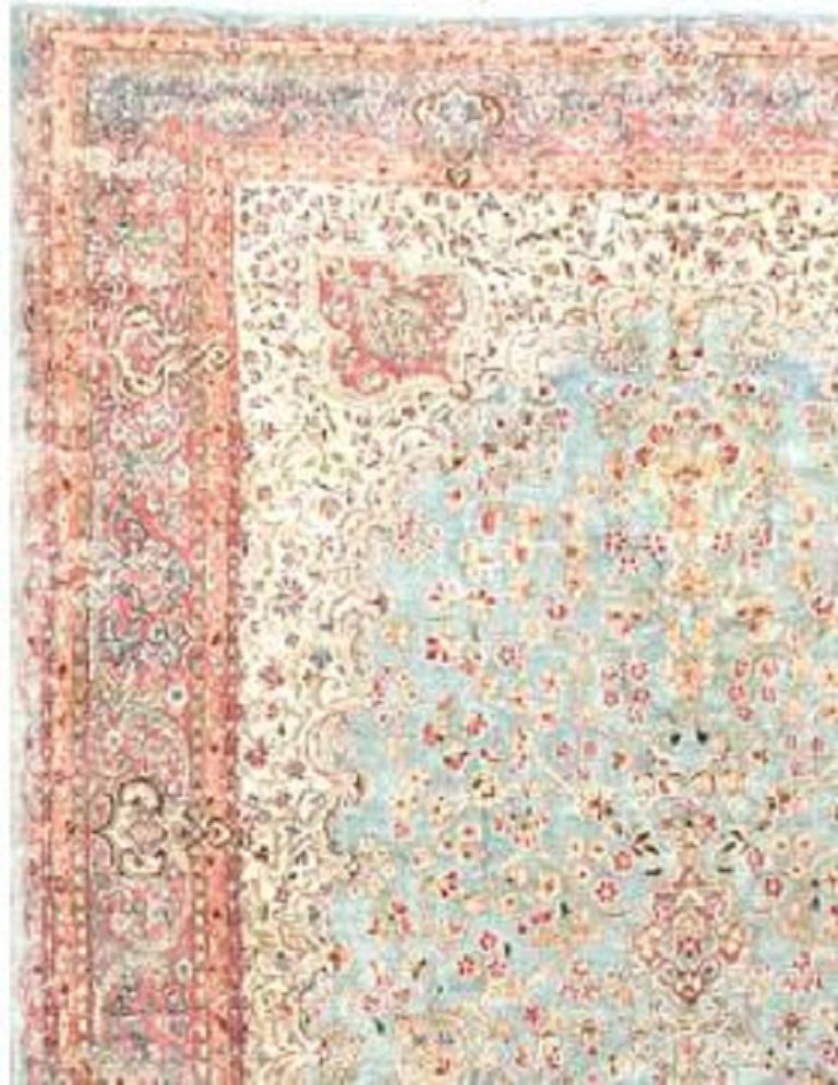 A dramatic antique Kirman rug of an unusual size. The powder blue field filled with flowers surrounding a central medallion in navy and ivory surrounded by a border with peach elements. Kirman is the capital of the province in south Persia of the
