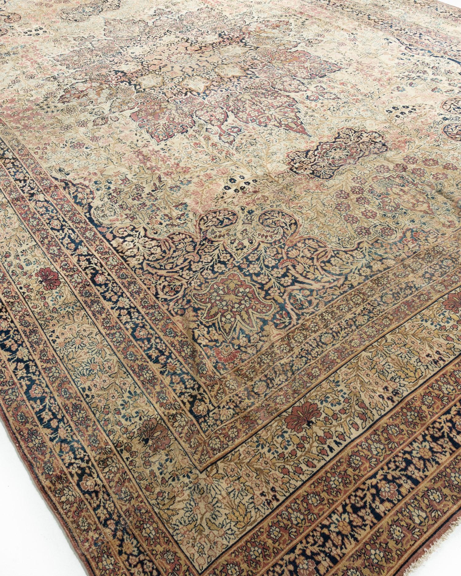 Antiker persischer Kirman-Teppich, um 1880. Größe: 10'10 x 16'3. Ein kaleidoskopisches Blumenmedaillon in einer Vielzahl von Farben zentriert das Design dieses antiken Kirman-Teppichs, der in der südpersischen Stadt Kirman gewebt wurde. Botanische