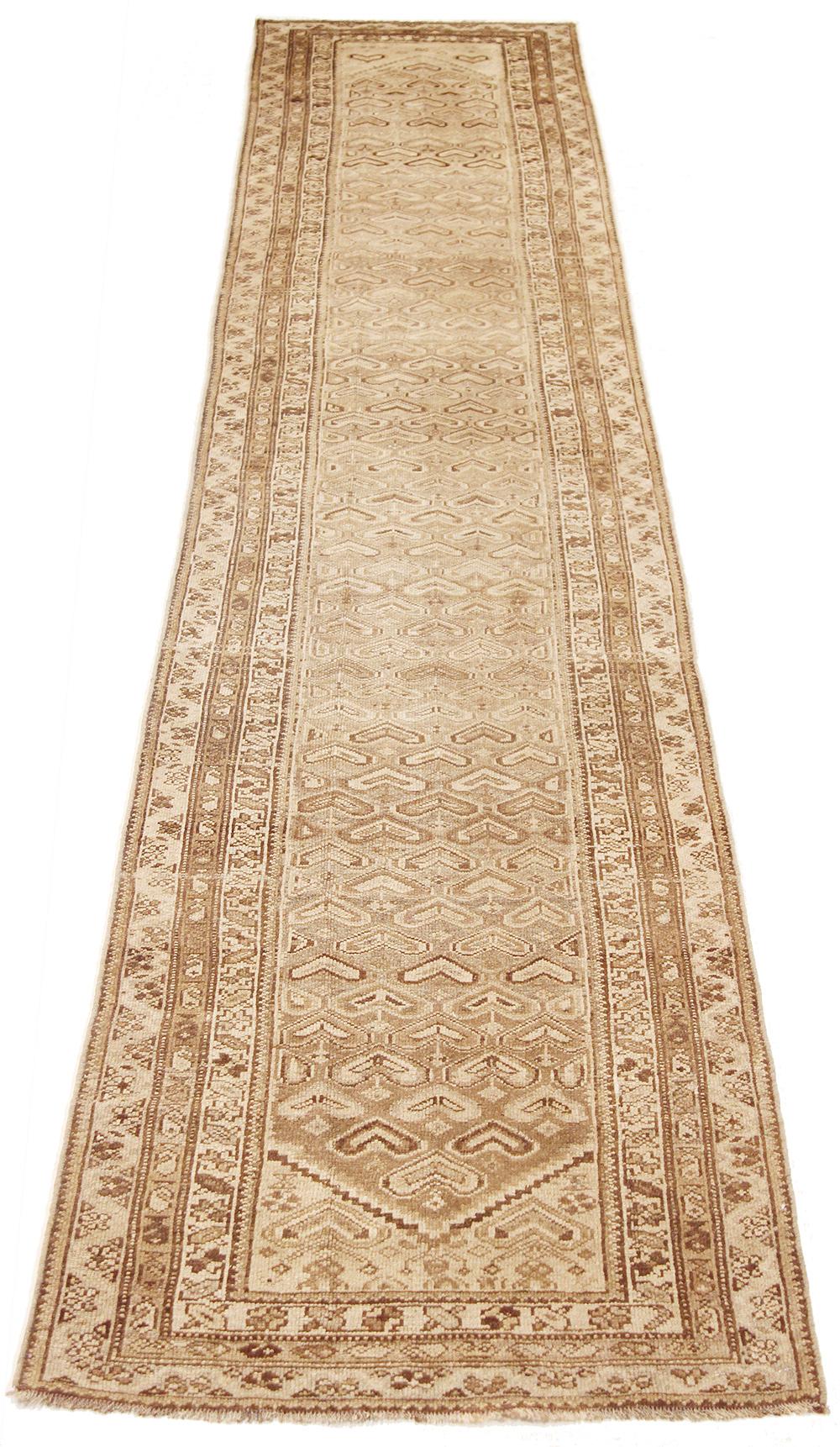 Antique Persian runner rug handwoven from the finest sheep’s wool and colored with all-natural vegetable dyes that are safe for humans and pets. It’s a traditional Koliai design featuring heart-shaped details in ivory and brown over a beige field.