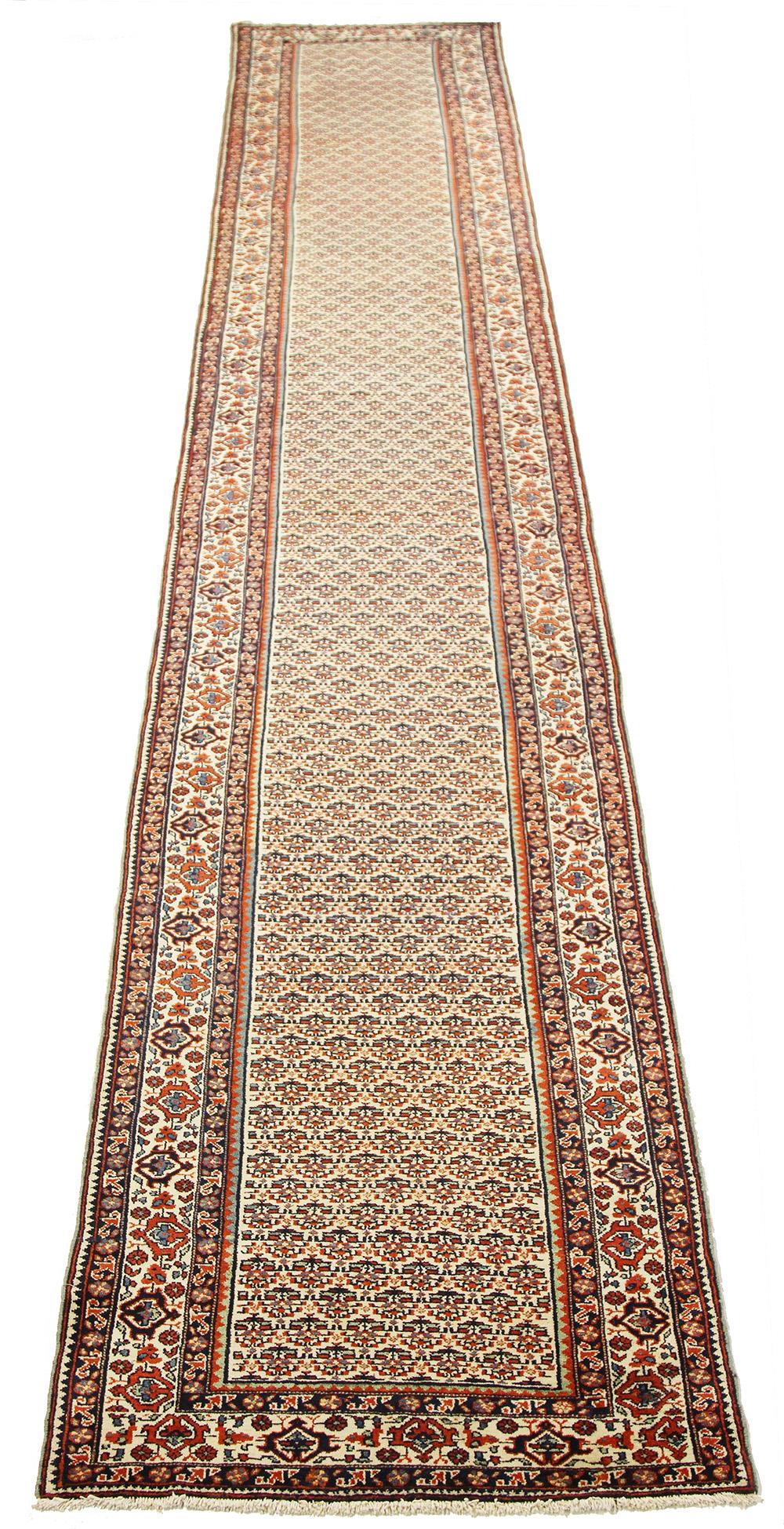 Antique Persian runner rug handwoven from the finest sheep’s wool and colored with all-natural vegetable dyes that are safe for humans and pets. It’s a traditional Kordi design featuring floral details in red and black over an ivory field. It’s a