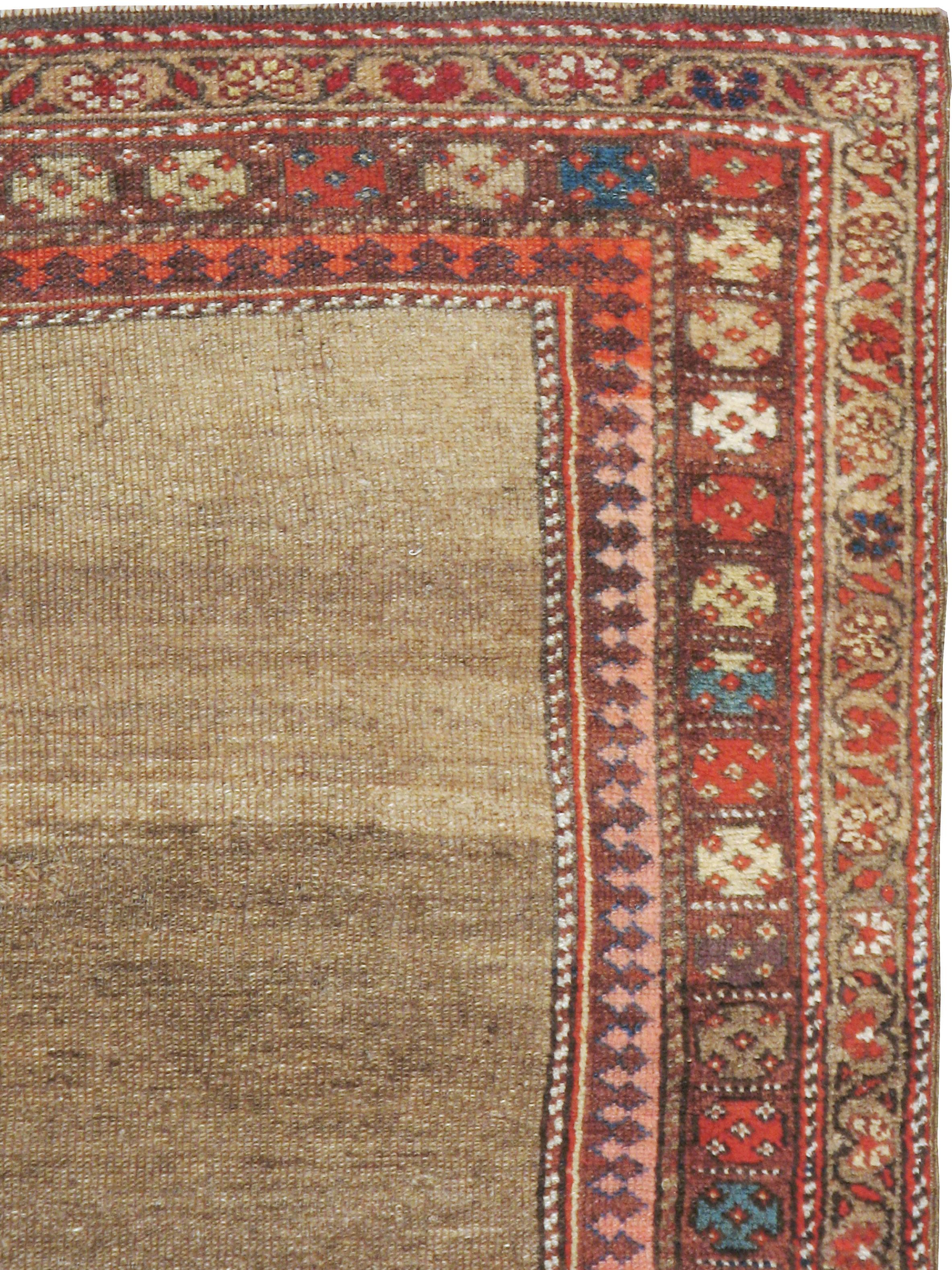 An antique Persian Kurdish rug from the early 20th century. The light camel plain field is attractively abrashed (naturally striated) and is bordered by a rosette on a rust ground.

•Hand knotted in Persia
•Wool
•One-of-a-kind.
