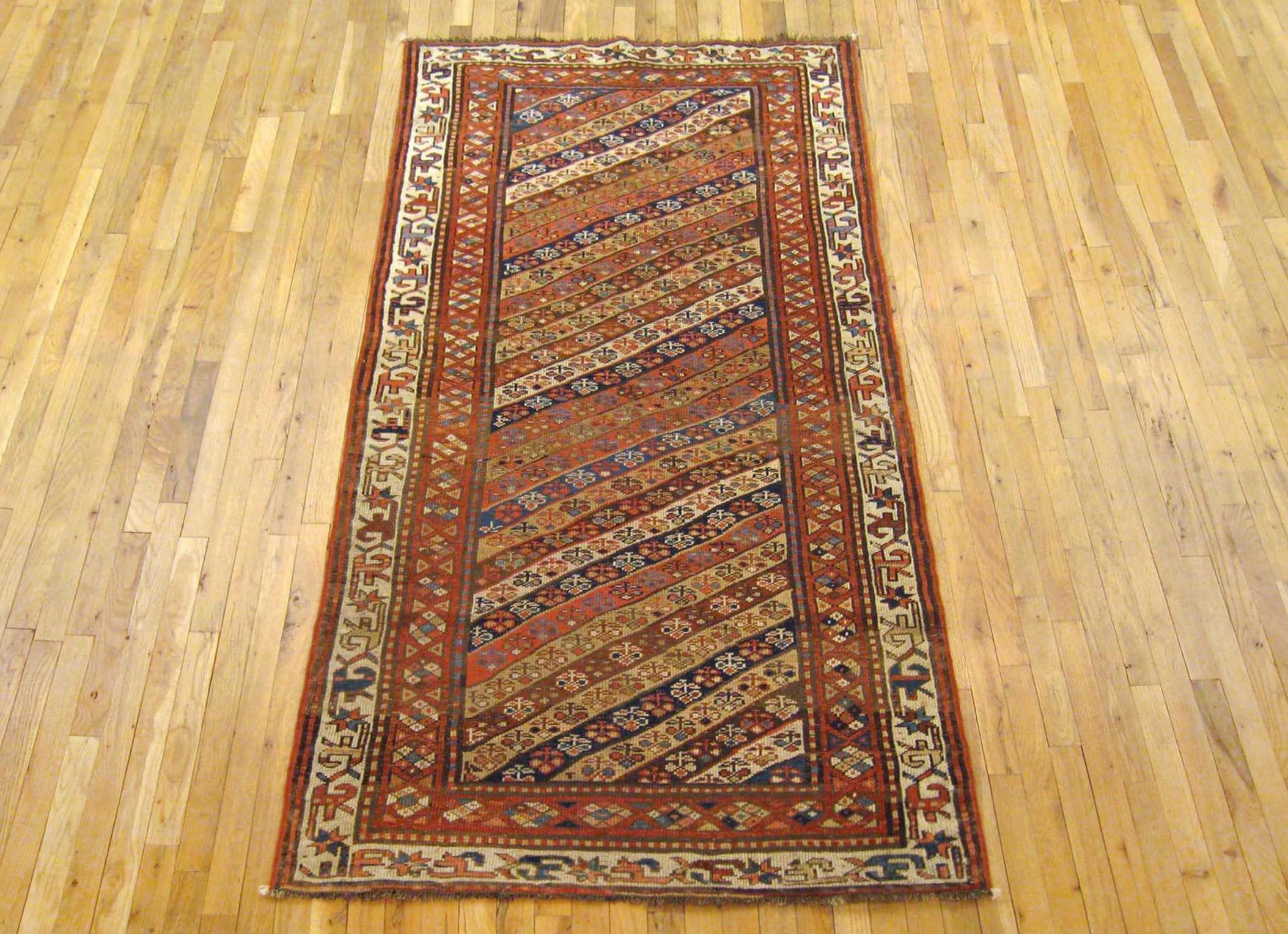 Antique Persian Kurd Rug, Runner size, circa 1900.

A one-of-a-kind antique Persian Kurd Oriental Carpet, hand-knotted with soft wool pile. This rug features diagonal stripes allover the red primary field, within an ivory outer border. In runner