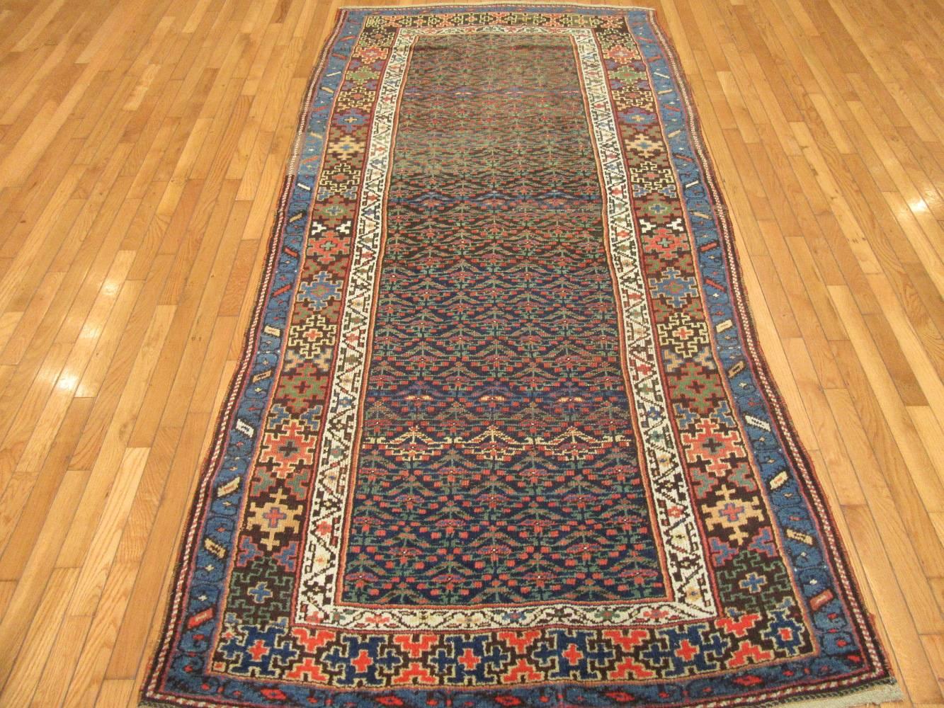 This is an antique hand-knotted rug from the Kurdish region of western Iran. This rug is made with all wool colored with natural dyes in around the turn of the century. It has a detailed repetitive floral motifs on a royal blue color background. It