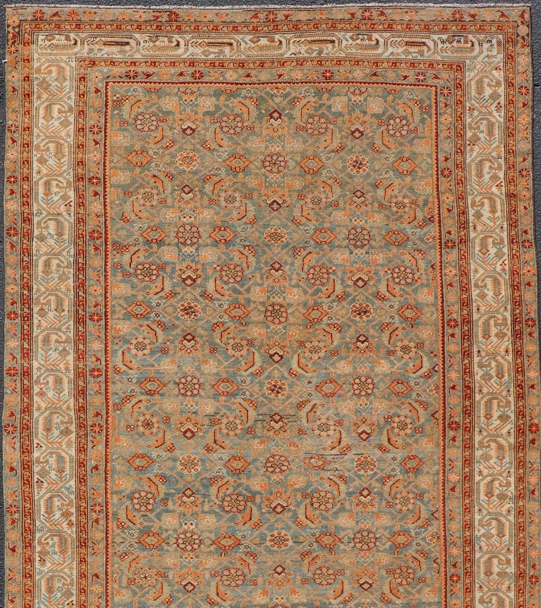 Measures: 5'8 x 14'0 

This antique Persian Kurdish gallery rug is filled with eccentric colors and details. The multi-tiered border features nature motifs rendered in the same colors of the field. The field design is rendered in orange, red,