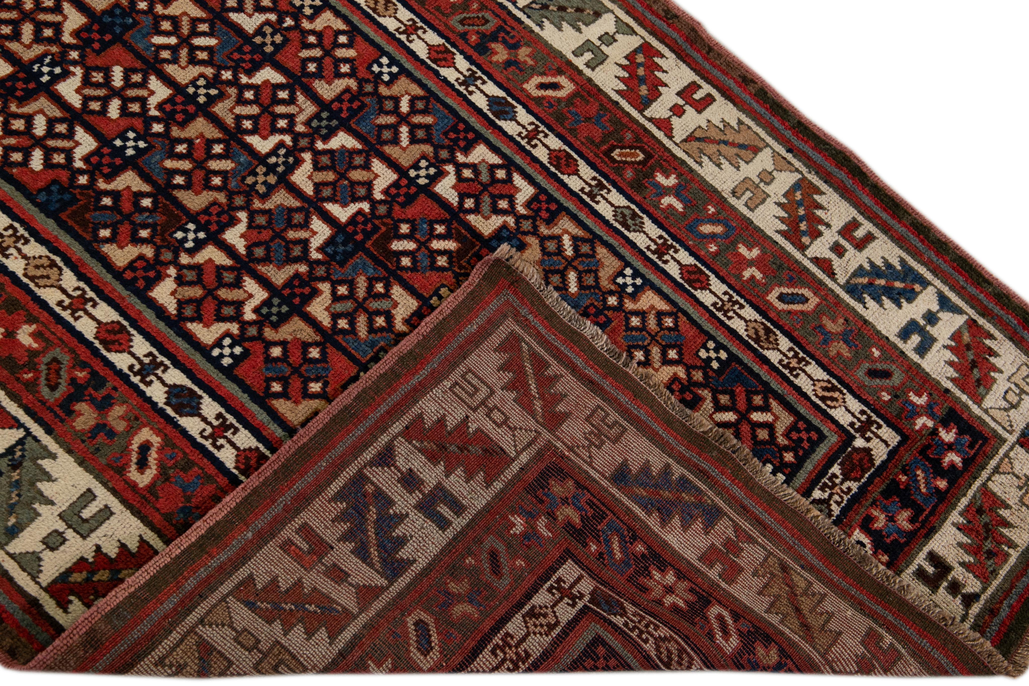 Beautiful Kurdish hand-knotted wool runner with a geometric design on a red field. Accents of blue, beige, and green throughout the piece. 

This rug measures 3'1