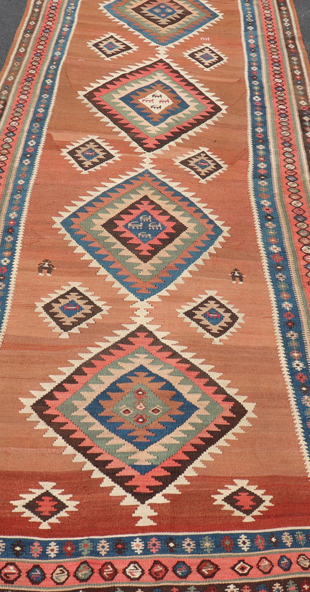 Tapis de galerie Kilim persan kurde ancien à motifs de médaillons géométriques. Keivan Woven Arts / tapis X23-0610-1876, pays d'origine / type : Iran / Kilim, circa 1910
Mesures : 4'11 x 14'3 
Il est orné d'un médaillon géométrique en forme de