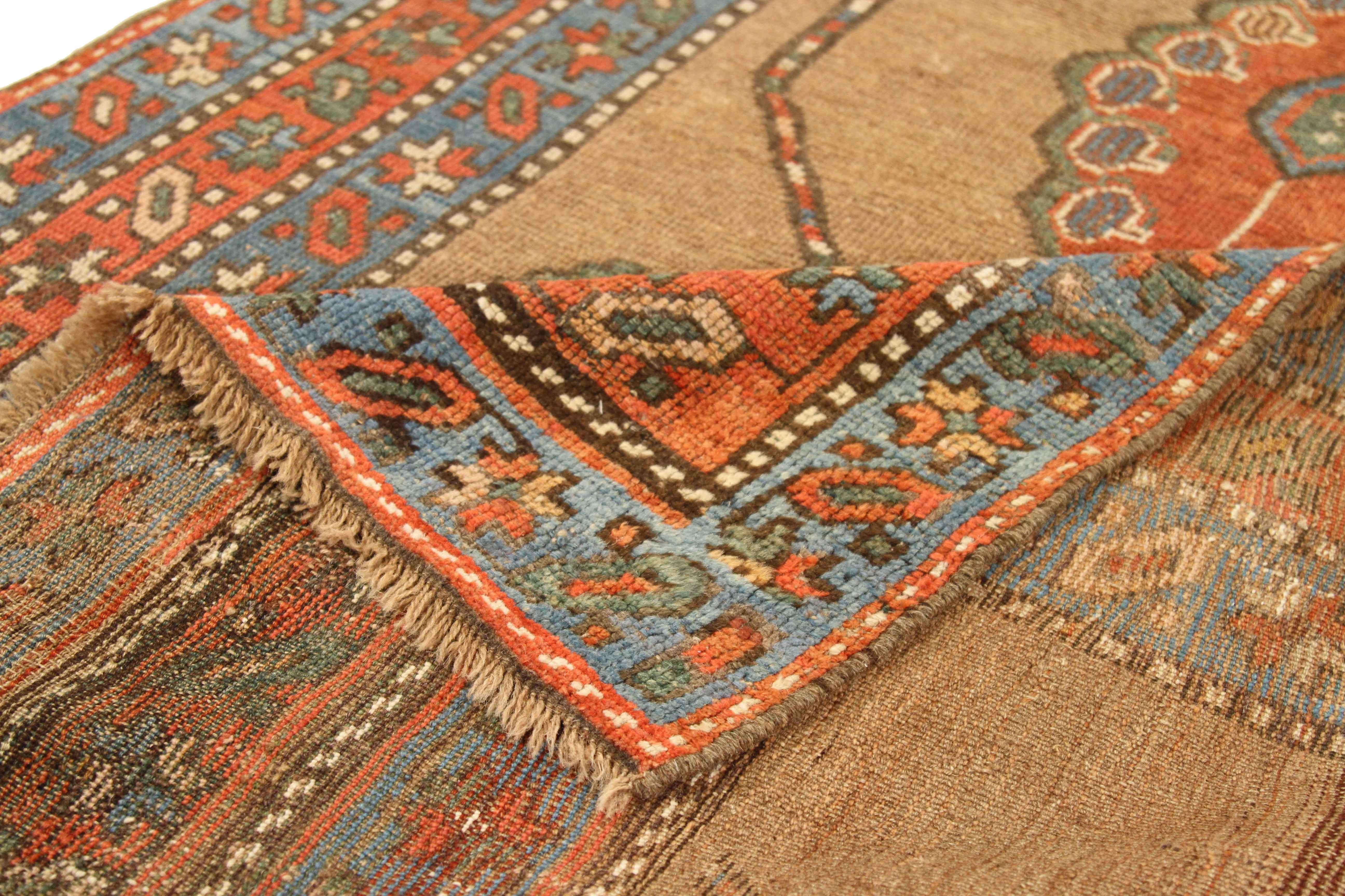 Antique Persian rug handwoven from the finest sheep’s wool and colored with all-natural vegetable dyes that are safe for humans and pets. It’s a traditional Kurdish design highlighted by large and small geometric medallions in blue and orange over a