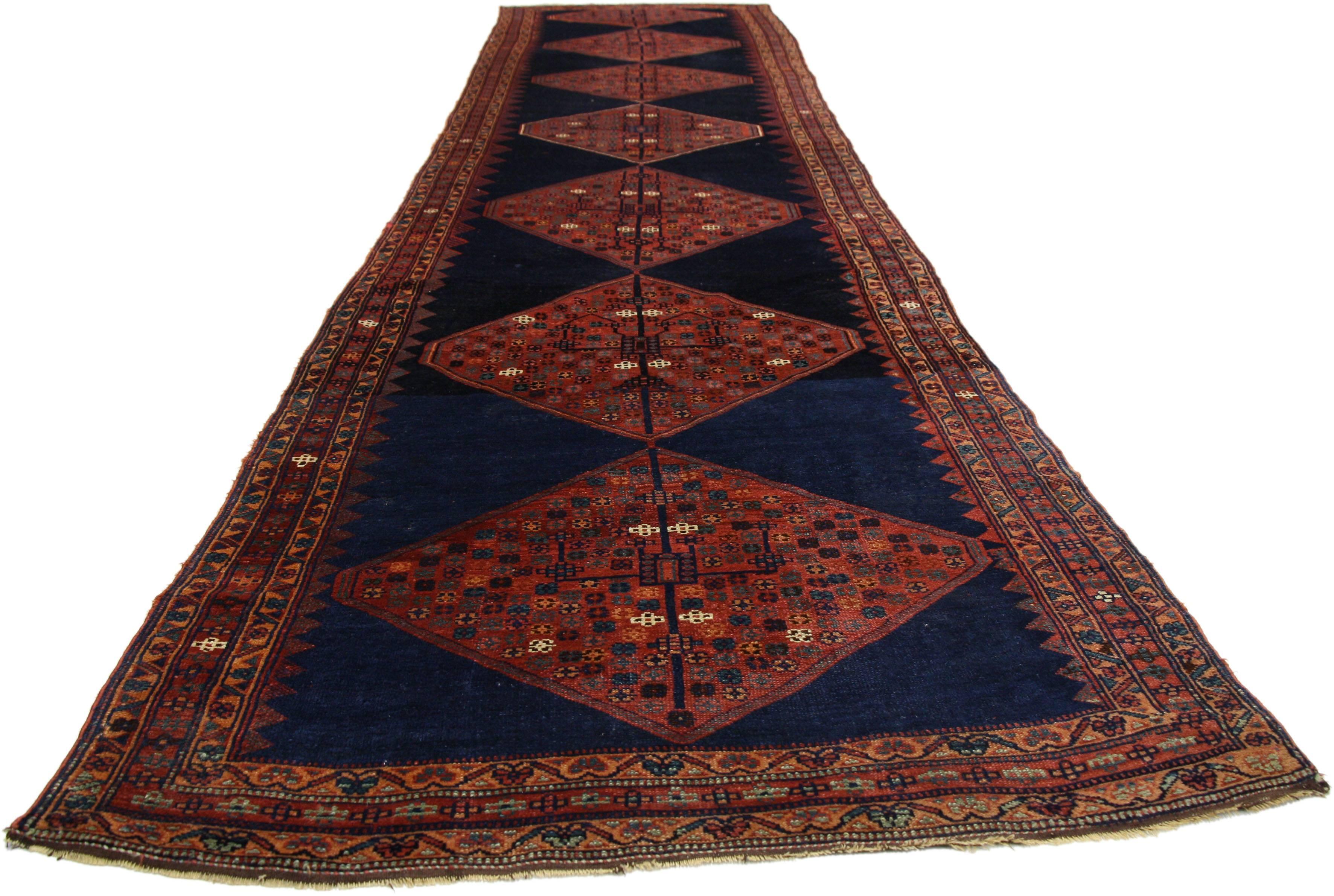 77151, antique Persian Kurdish runner, extra-long hallway runner. This hand knotted antique Persian Kurdish runner features seven diamond shaped lozenges on an abrashed ink blue field. Frenzied gardens of stylized flowers fill the stacked lozenge