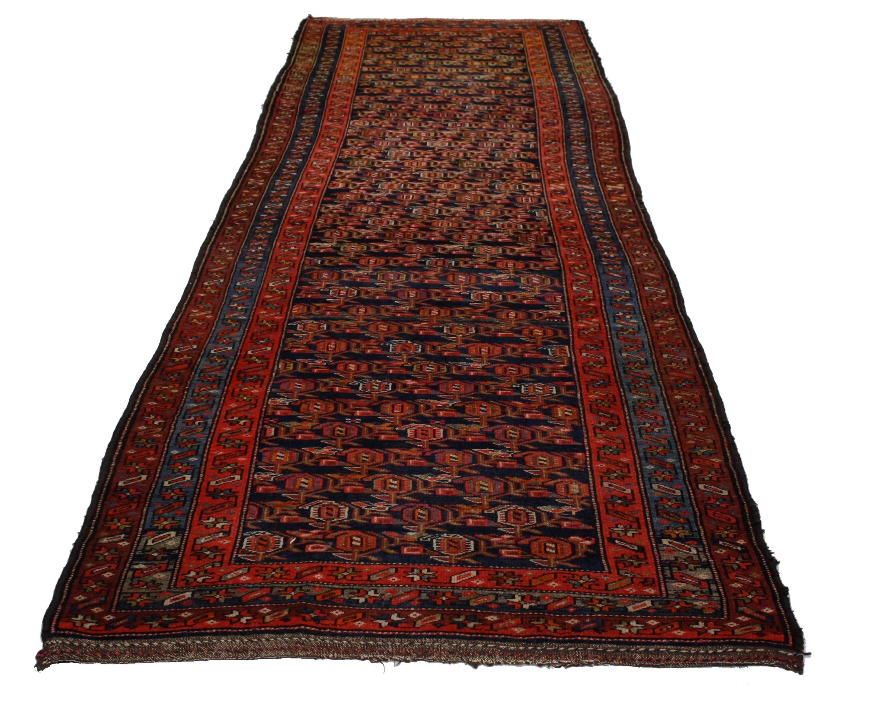 76615 antique Persian Kurdish runner, long Kurd Hallway runner. This hand-knotted wool antique Persian Kurdish runner features an all-over Boteh design pattern on an ink blue background. The Boteh resembles sprouting seed and is known as the 